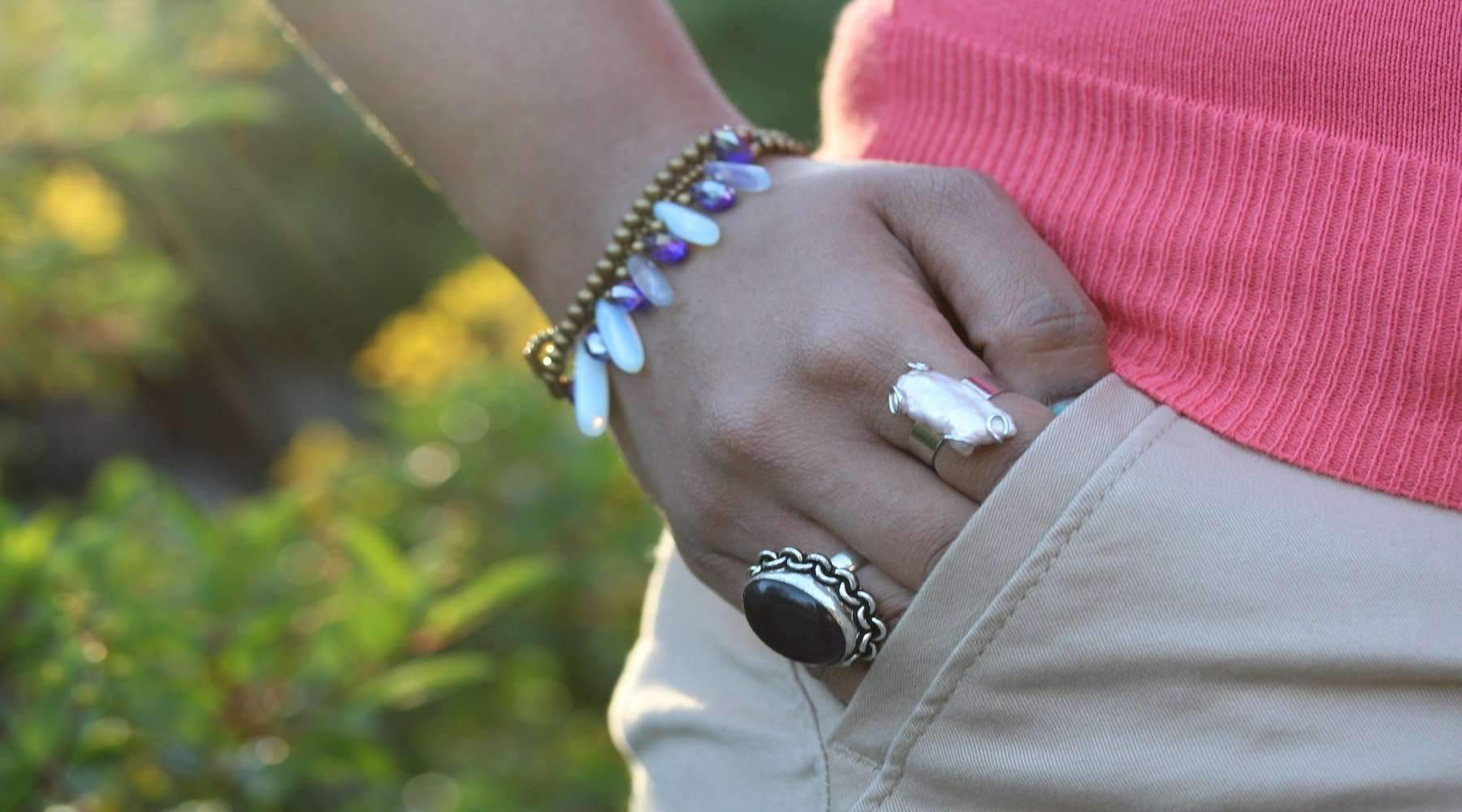 A handmade Opalite & Crystal Romance Bracelet featuring blue opalized glass tube beads, crystal beads, and brass accents, woven with a black chord.