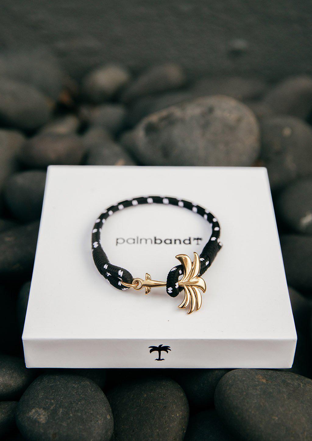 Trophy Palm Band featuring a gold palm tree anchor on a black and white nylon rope, symbolizing positivity and success.