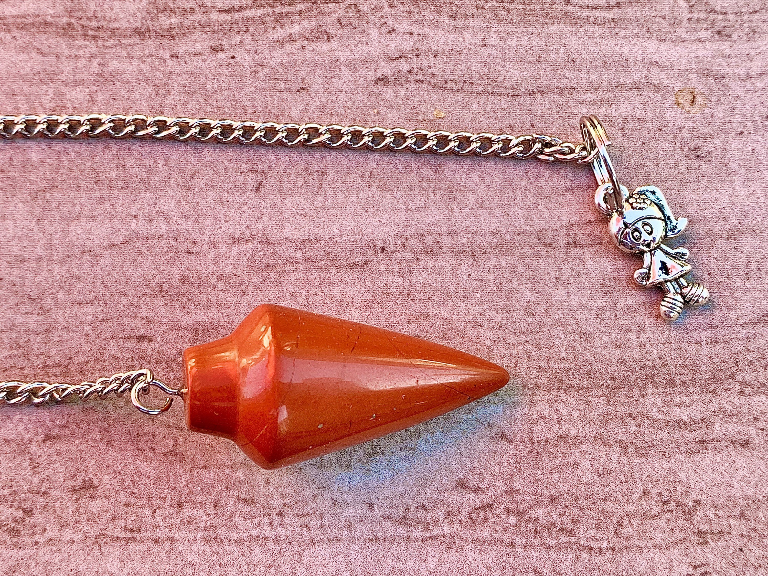 A stylish red jasper pendulum bracelet featuring polished stones and a delicate chain, perfect for dowsing and energy balancing.