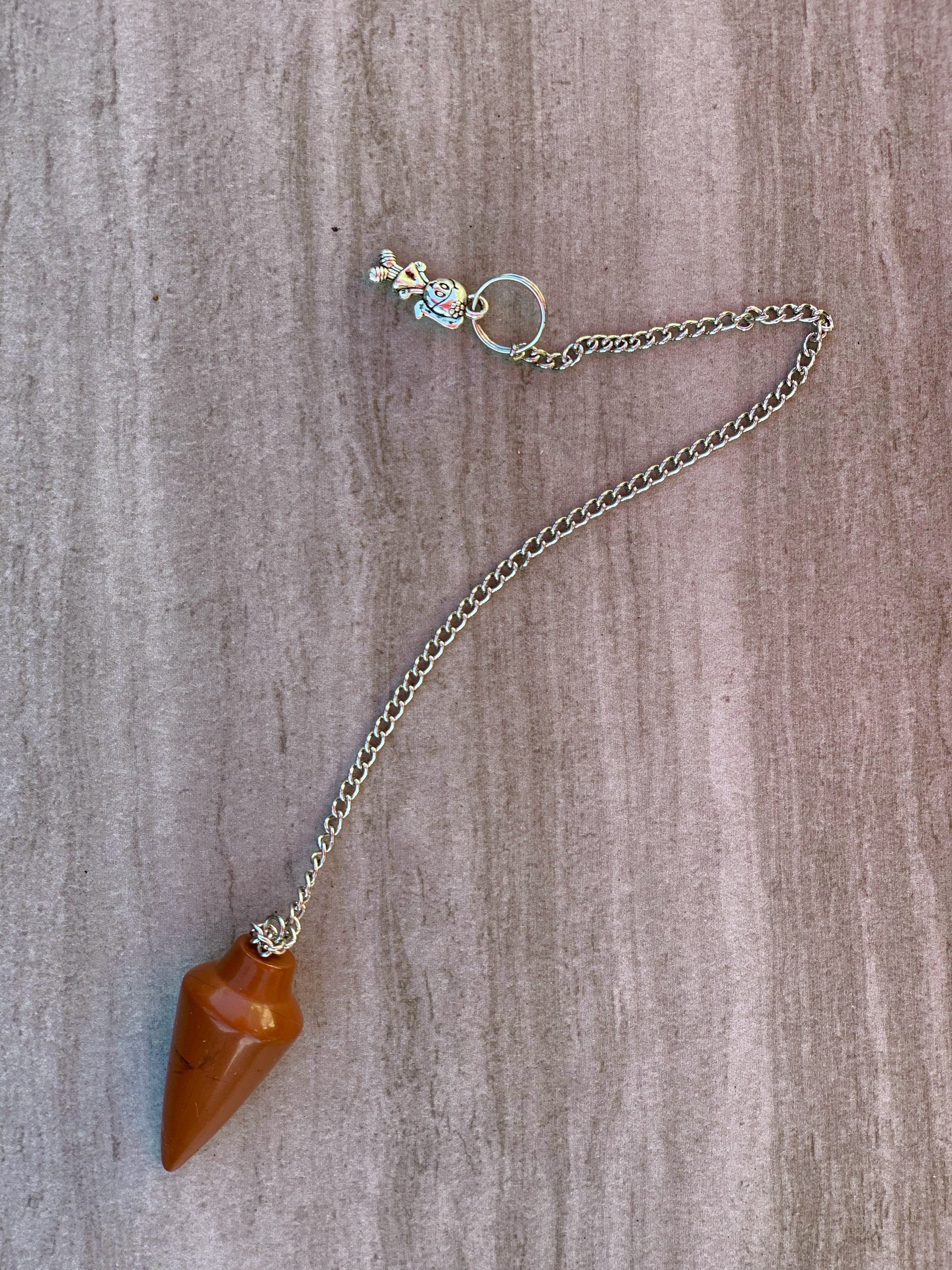 A stylish red jasper pendulum bracelet featuring polished stones and a delicate chain, perfect for dowsing and energy balancing.