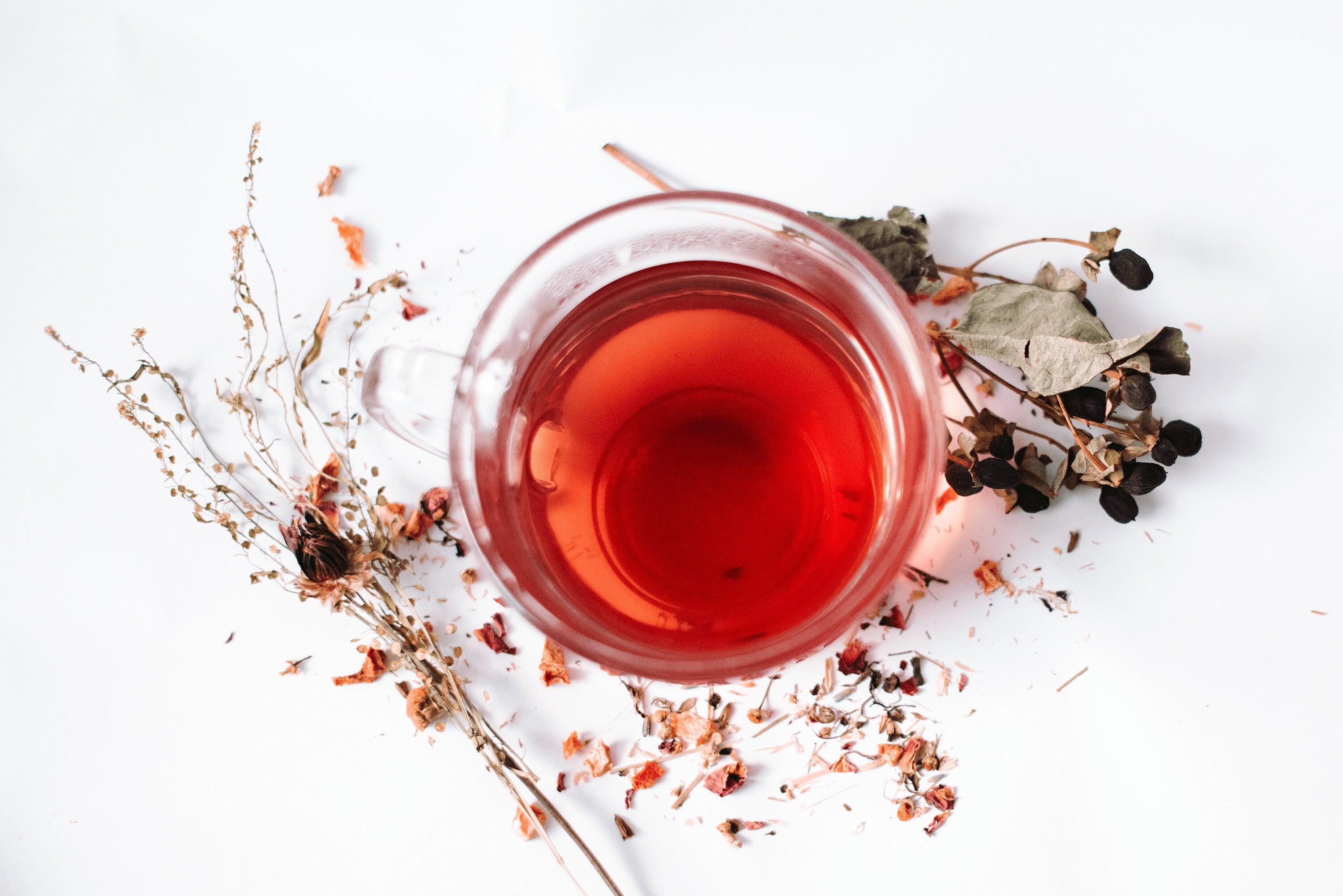 A calming blend of loose leaf Rest Sleep Time Tea with lavender and chamomile in a clear glass cup, surrounded by dried lavender flowers.