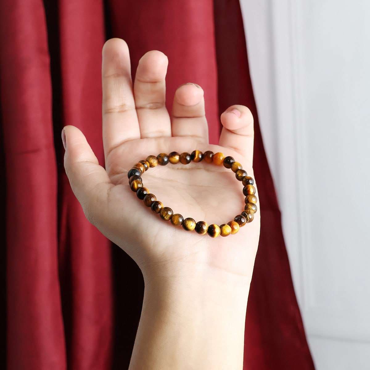 A close-up view of a Tiger Eye Round Beads Bracelet showcasing its natural golden-brown hues and round beads, elegantly strung on elastic.