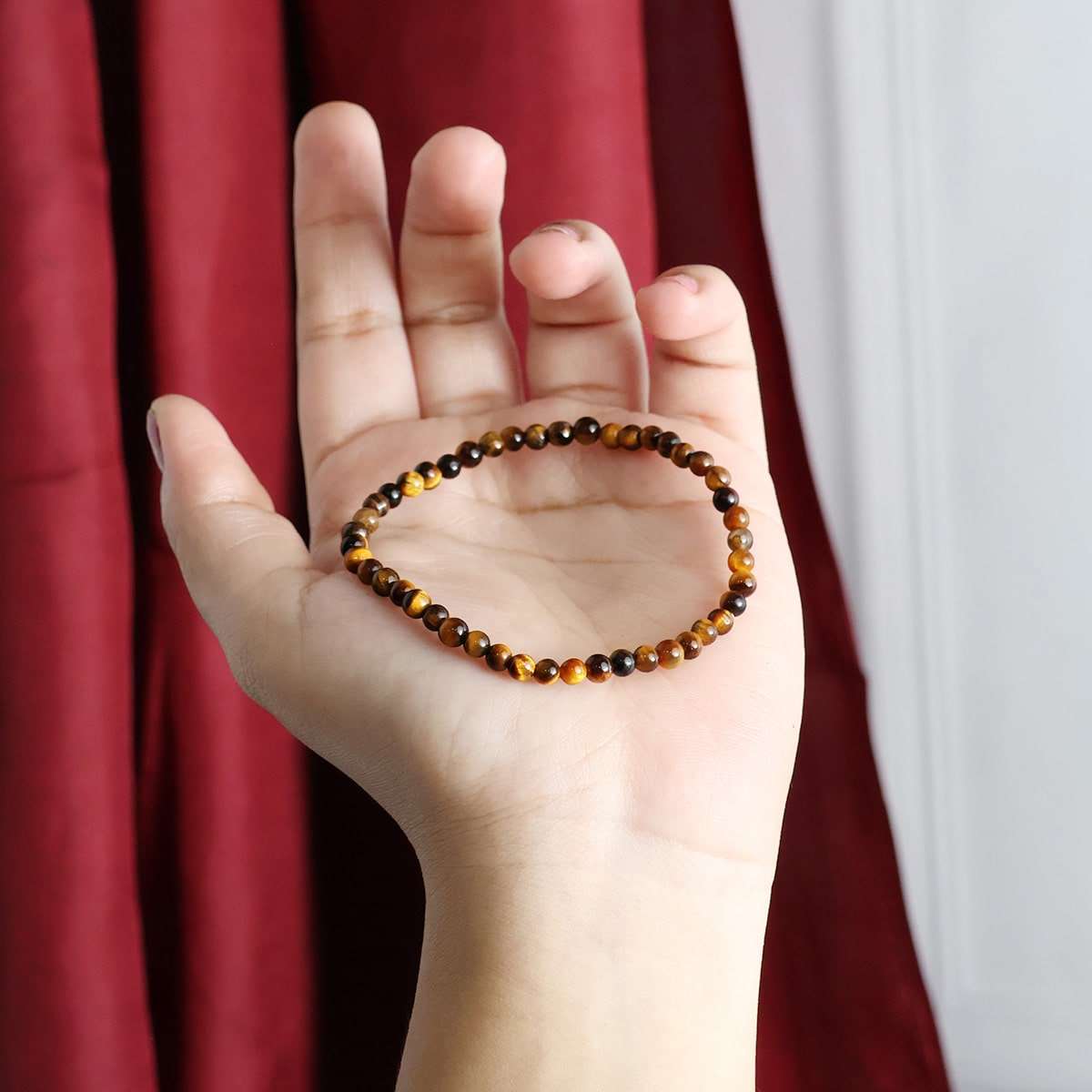 A close-up view of a Tiger Eye Round Beads Bracelet showcasing its natural golden-brown hues and round beads, elegantly strung on elastic.