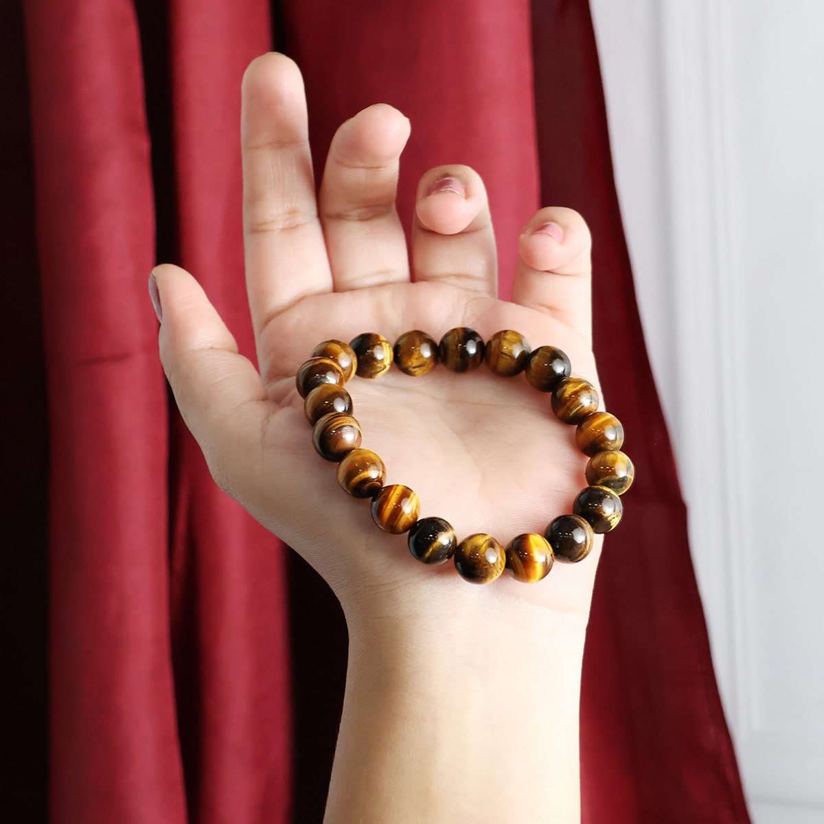 A close-up view of a Tiger Eye Round Beads Bracelet showcasing its natural golden-brown hues and round beads, elegantly strung on elastic.