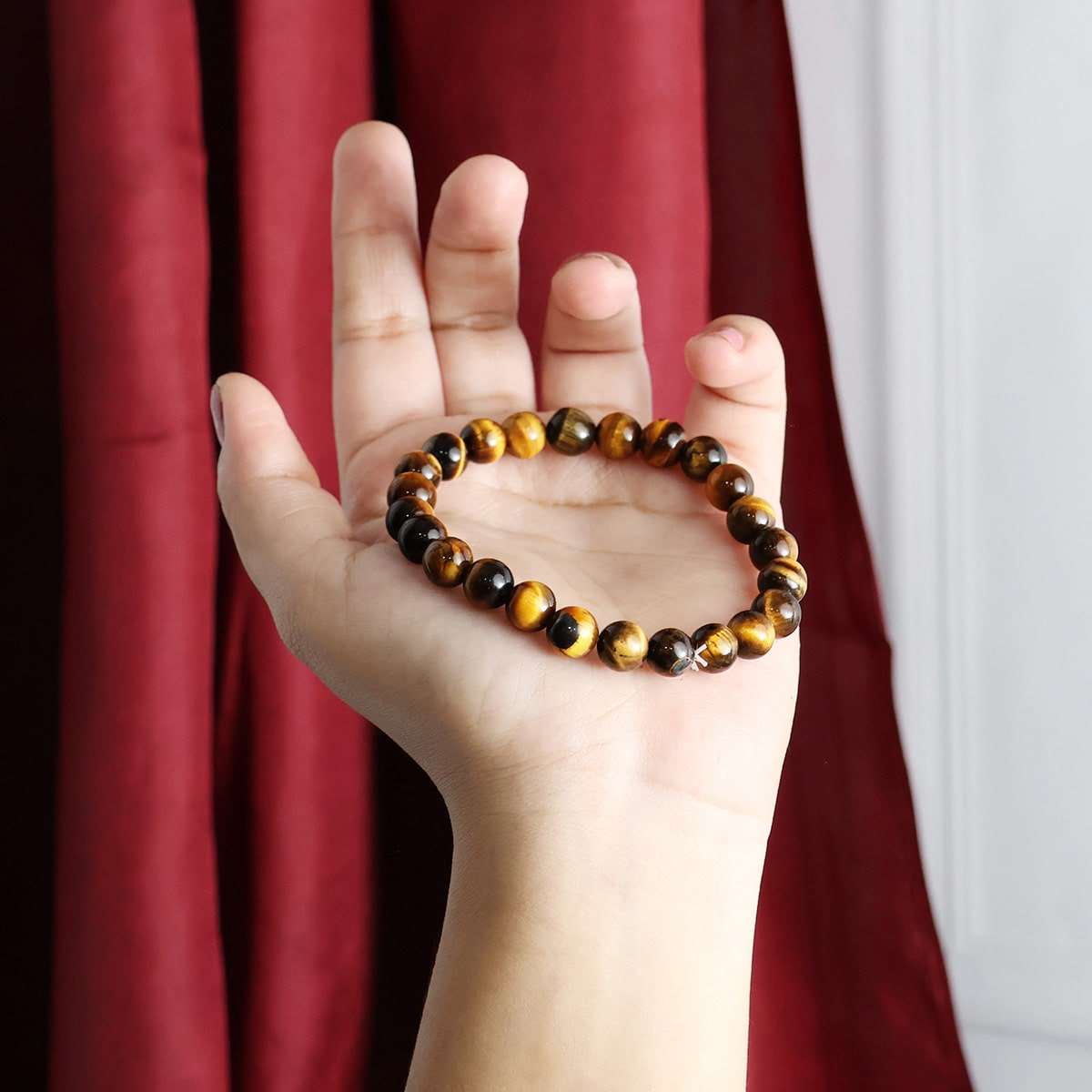 A close-up view of a Tiger Eye Round Beads Bracelet showcasing its natural golden-brown hues and round beads, elegantly strung on elastic.