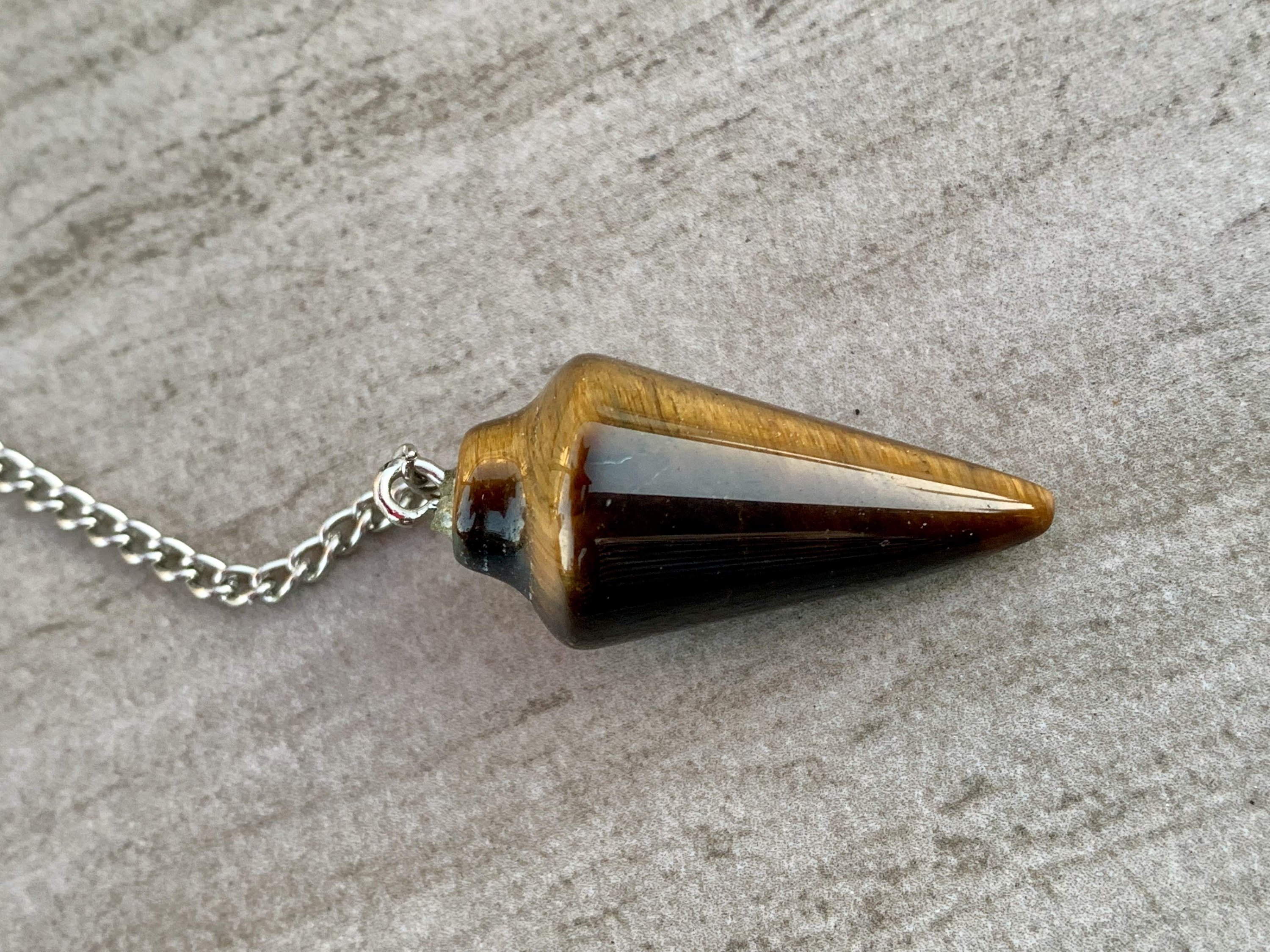 Tigers Eye Dowsing Pendulum and Bracelet showcasing golden yellow and deep yellow-brown hues with black stripes, symbolizing strength and grounding.