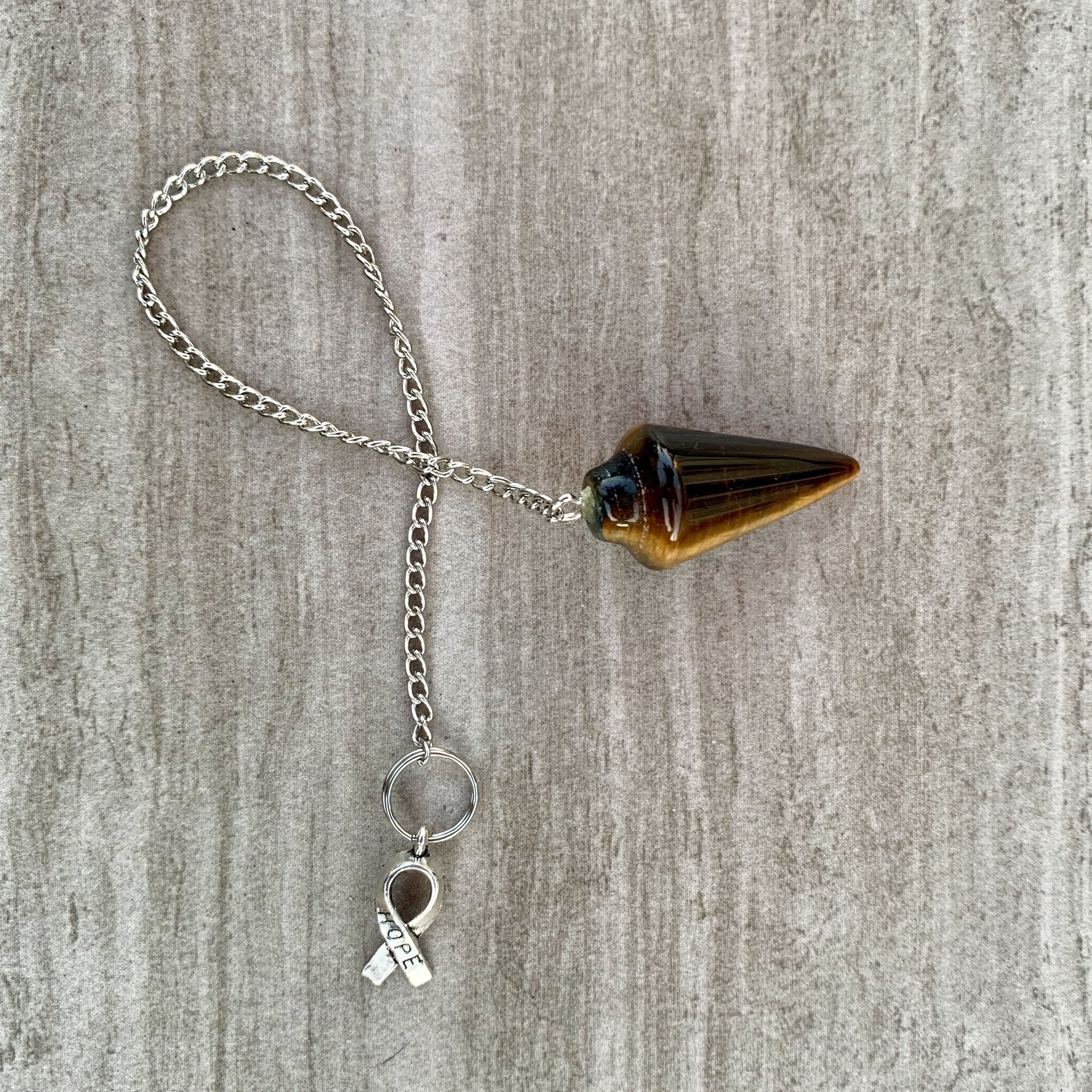 Tigers Eye Dowsing Pendulum and Bracelet showcasing golden yellow and deep yellow-brown hues with black stripes, symbolizing strength and grounding.