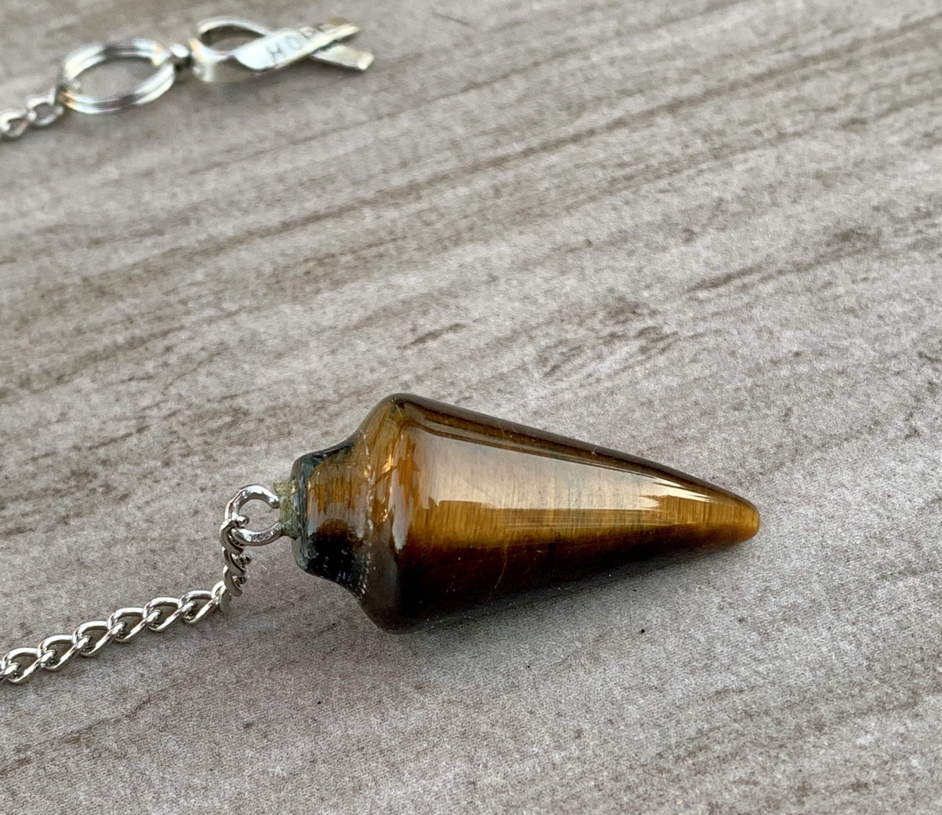 Tigers Eye Dowsing Pendulum and Bracelet showcasing golden yellow and deep yellow-brown hues with black stripes, symbolizing strength and grounding.