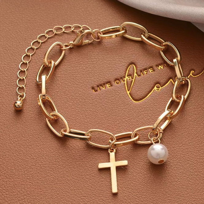 Women's oval link bracelet featuring a cross charm and faux pearl, elegantly designed in gold plated alloy.