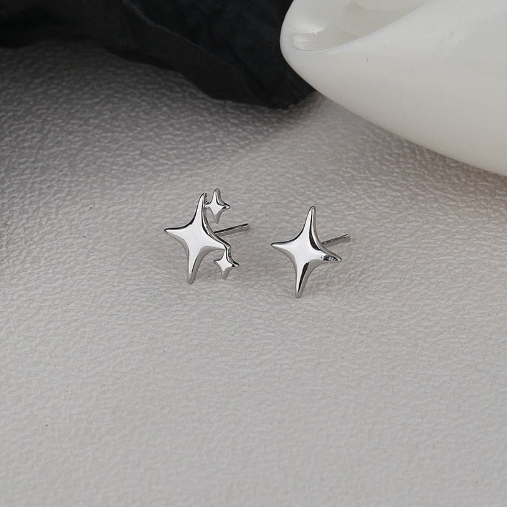 A pair of Asymmetrical Star Stud Earrings in gold and silver, showcasing a modern design with a smooth finish.