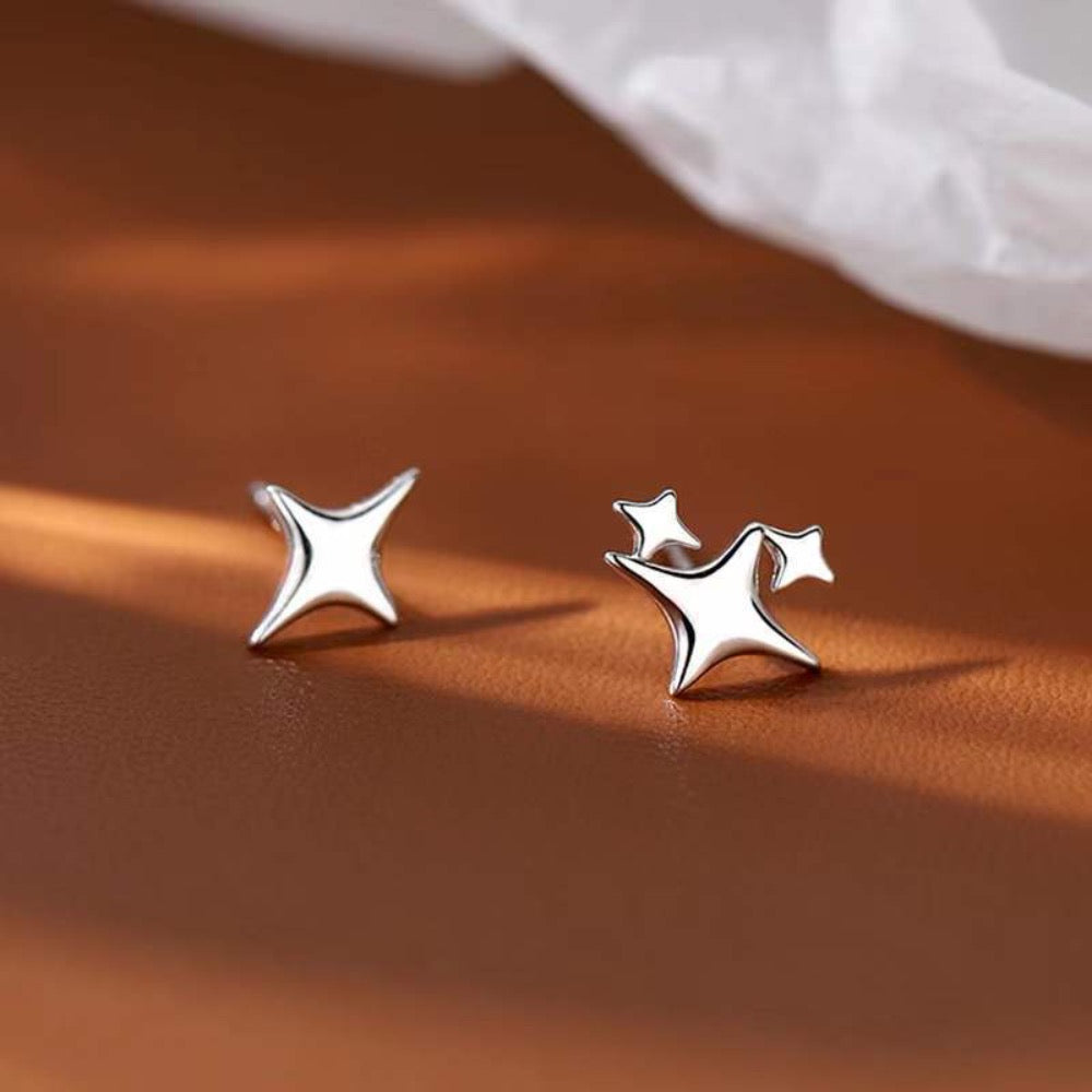 A pair of Asymmetrical Star Stud Earrings in gold and silver, showcasing a modern design with a smooth finish.