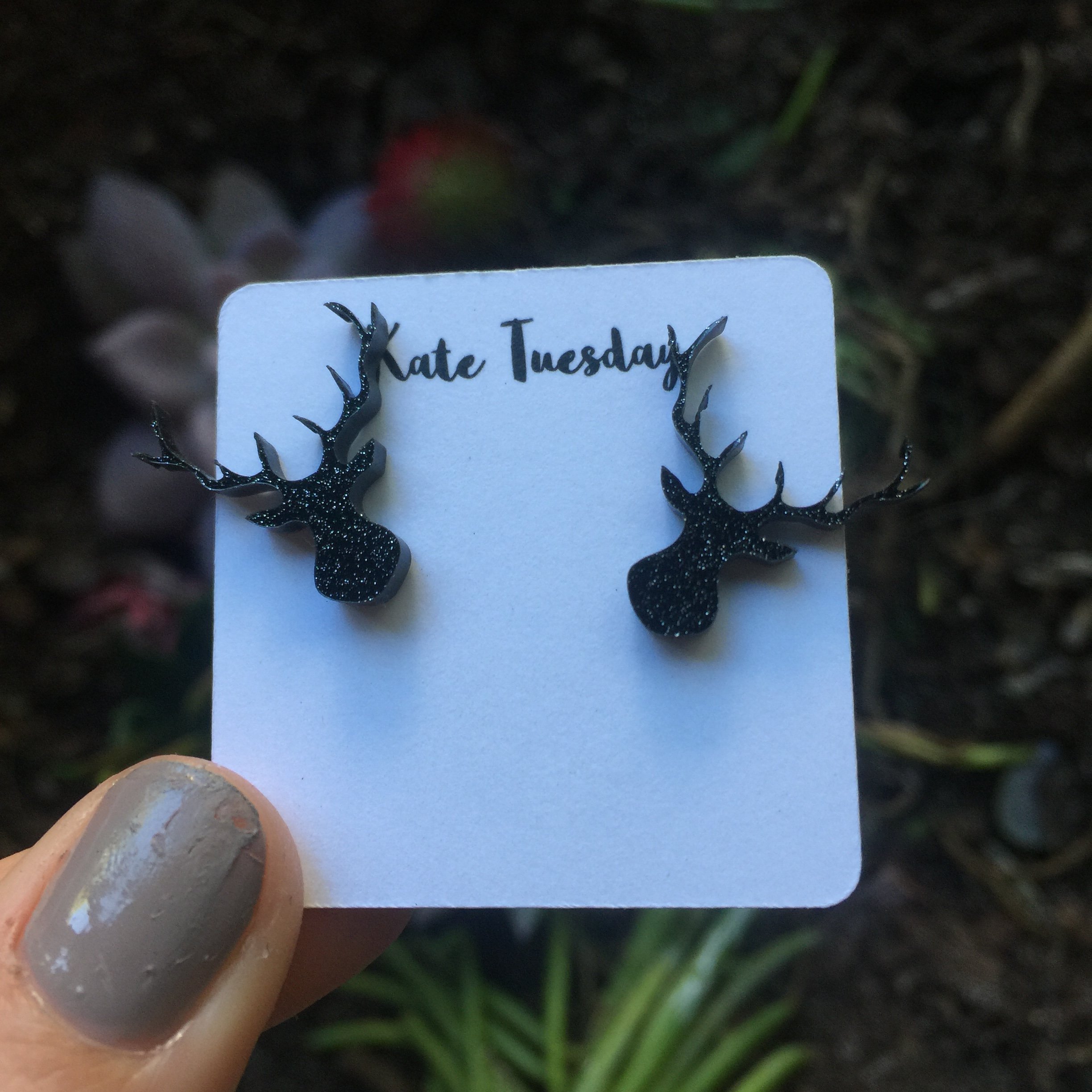 A pair of sparkly black antler stud earrings made from acrylic, showcasing a unique design perfect for stylish accessorizing.