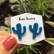 A pair of vibrant blue cactus-shaped sparkly acrylic earrings, showcasing their unique design and shimmering finish.