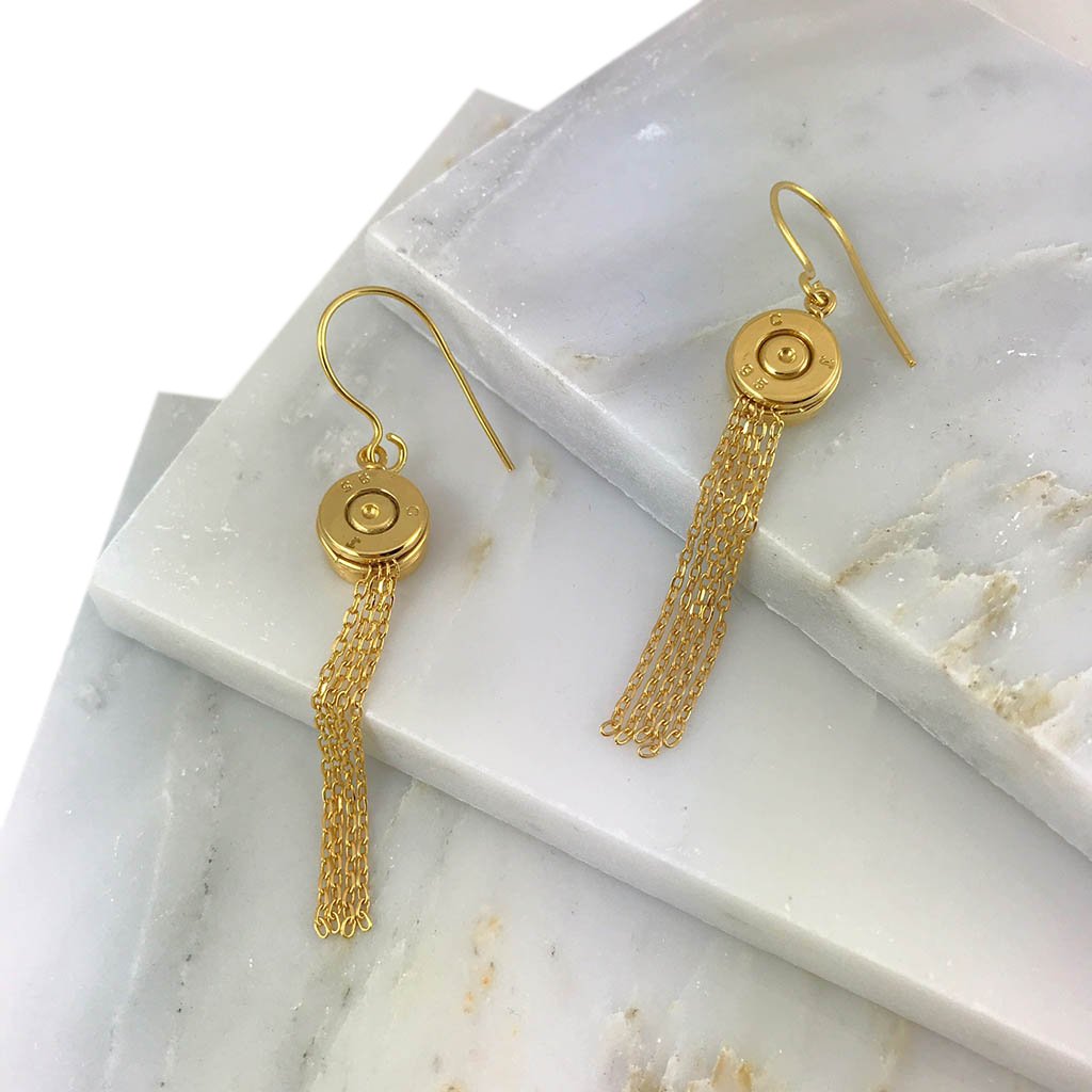 A pair of handmade Bullet Tassel Earrings featuring recycled brass bullet casings and gold-plated chains, showcasing their unique design.