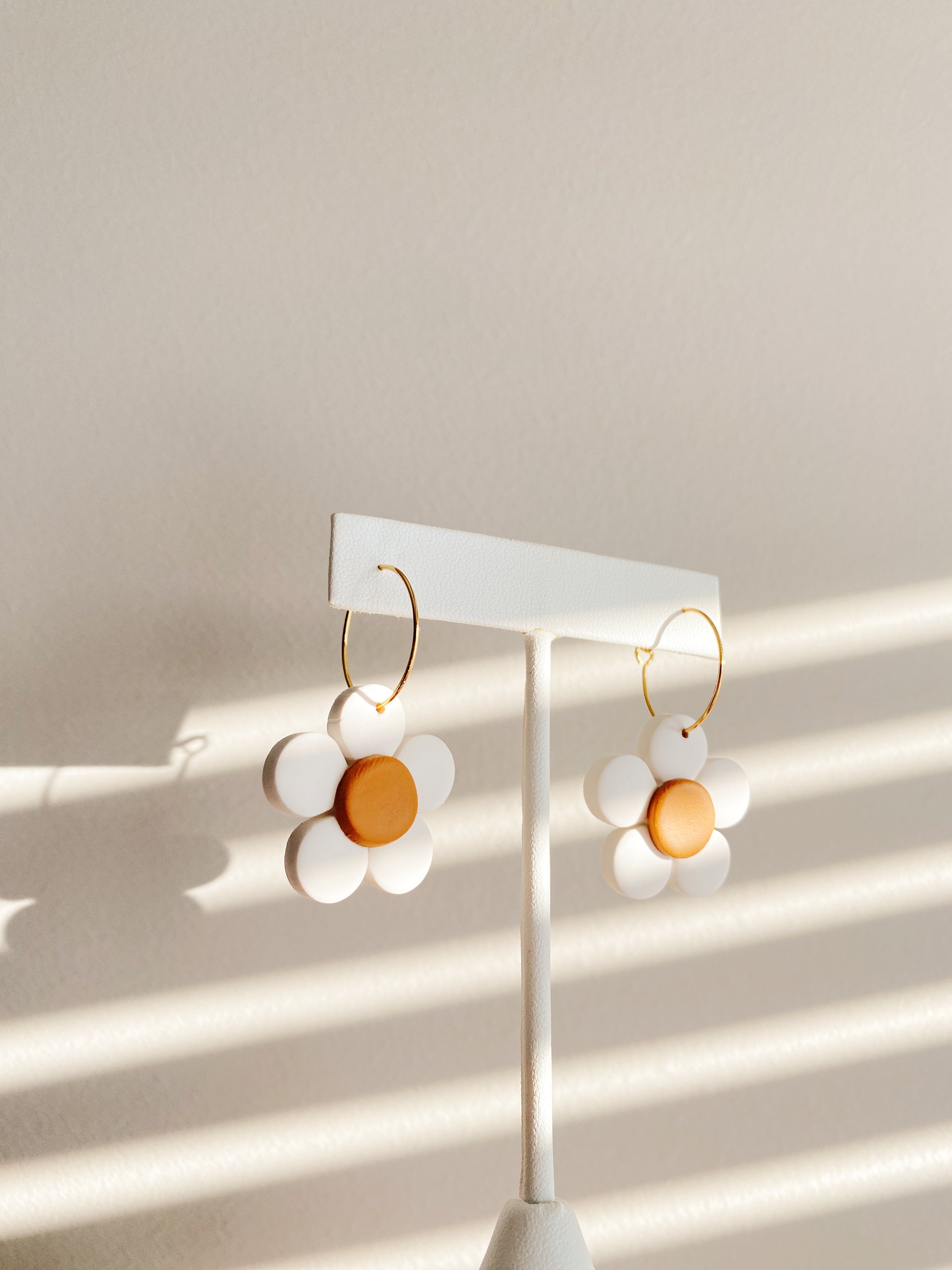 A pair of lightweight and hypoallergenic Daisy Hoops, handcrafted in Winnipeg, showcasing unique design and slight imperfections.