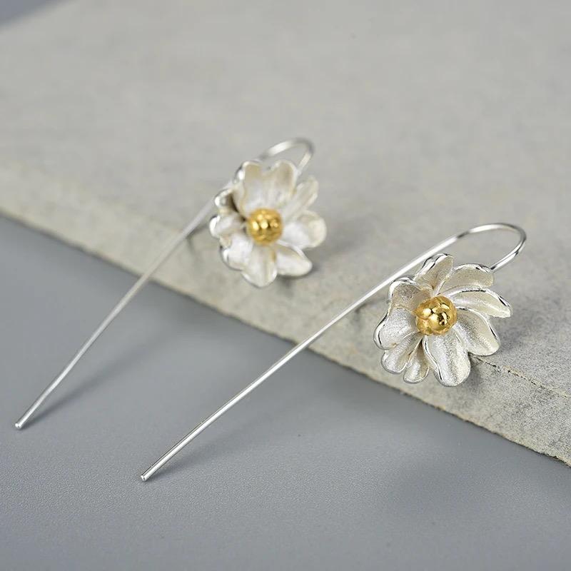 A pair of elegant silver earrings with intricate gold-plated floral designs, resembling delicate daisies, perfect for any occasion.