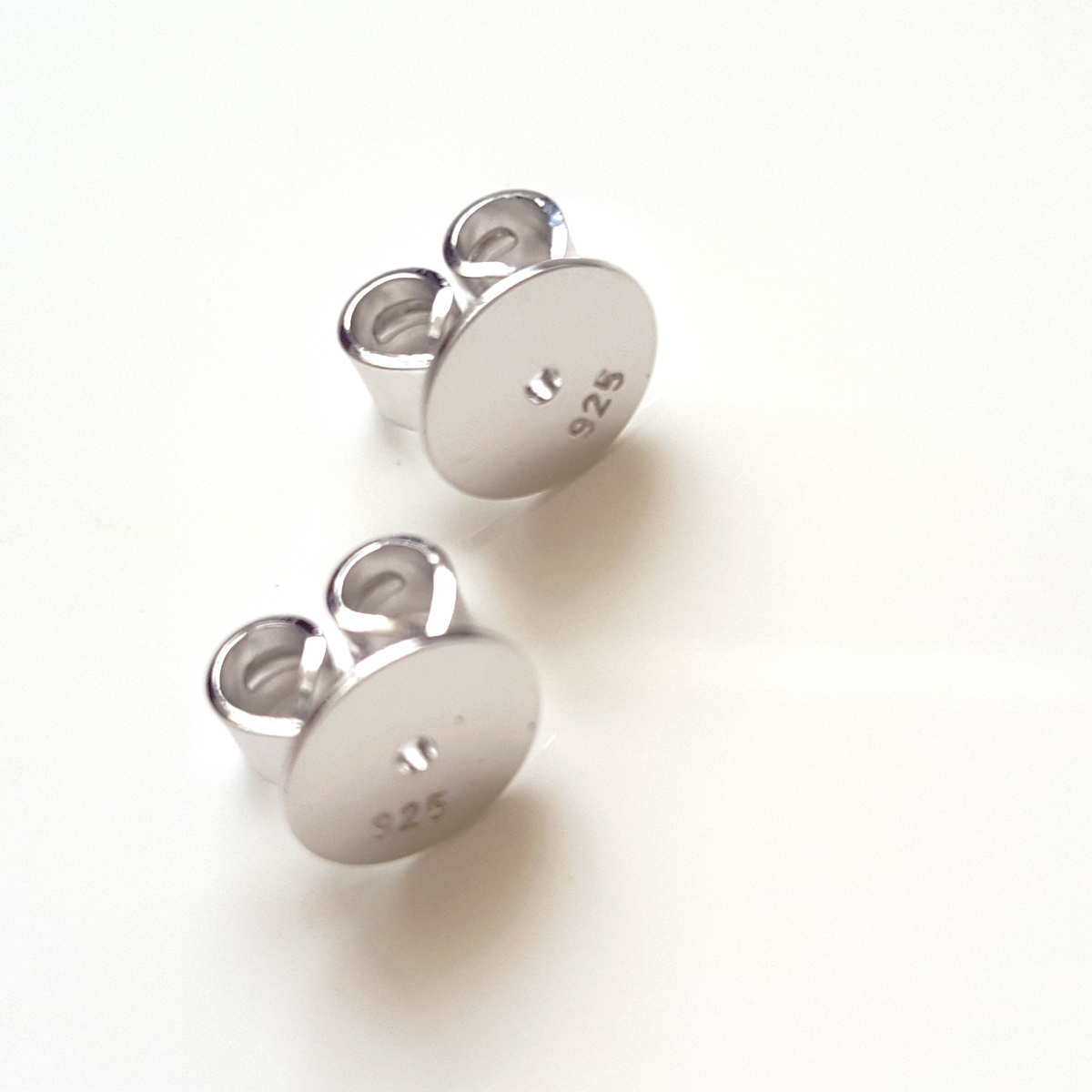 A pair of 6.5 mm sterling silver disc butterfly backs, showcasing their shiny finish and larger disc design for earring support.