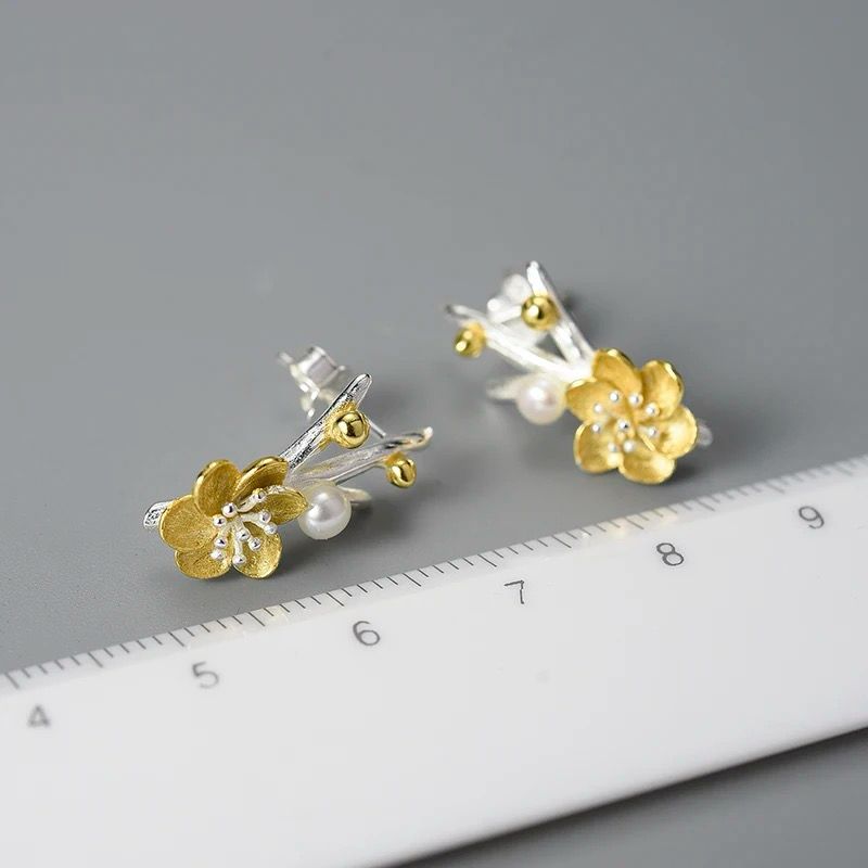 A pair of elegant flower earrings featuring a pearl accent, crafted from 925 silver and 18K gold plating.