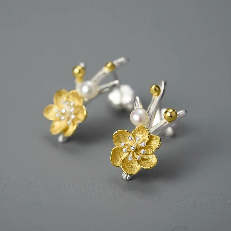 A pair of elegant flower earrings featuring a pearl accent, crafted from 925 silver and 18K gold plating.