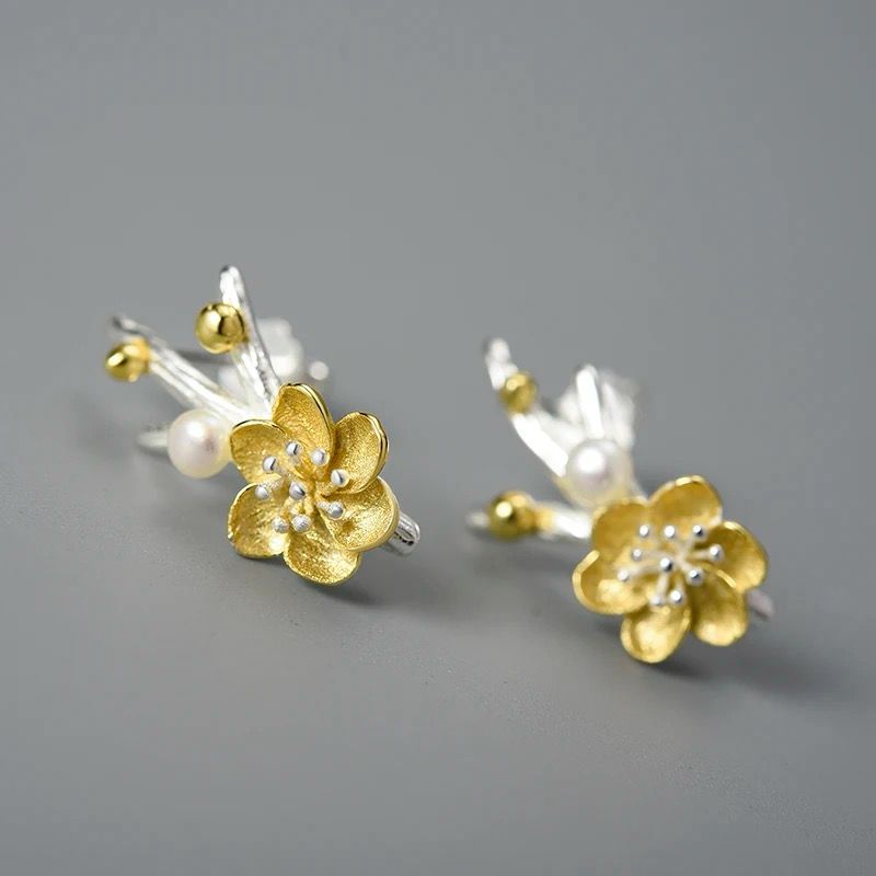 A pair of elegant flower earrings featuring a pearl accent, crafted from 925 silver and 18K gold plating.