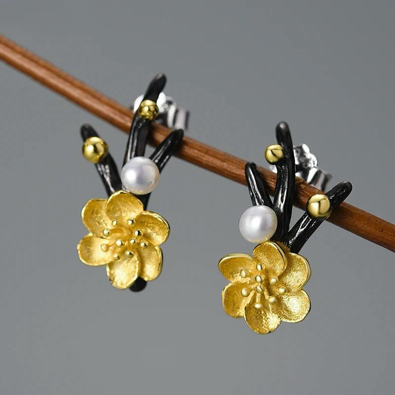 A pair of elegant flower earrings featuring a pearl accent, crafted from 925 silver and 18K gold plating.