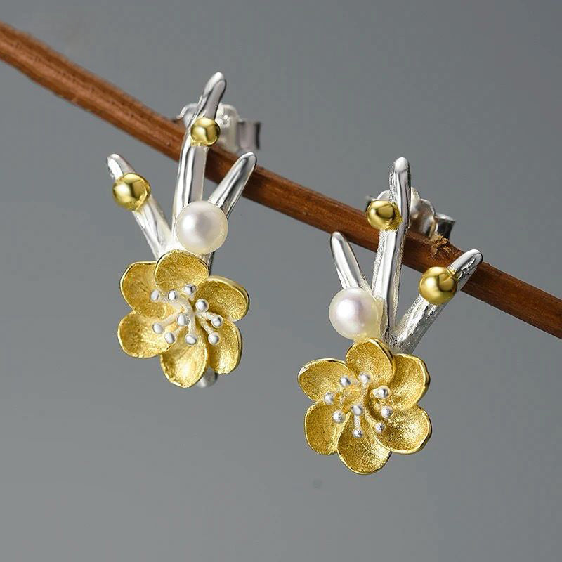 A pair of elegant flower earrings featuring a pearl accent, crafted from 925 silver and 18K gold plating.