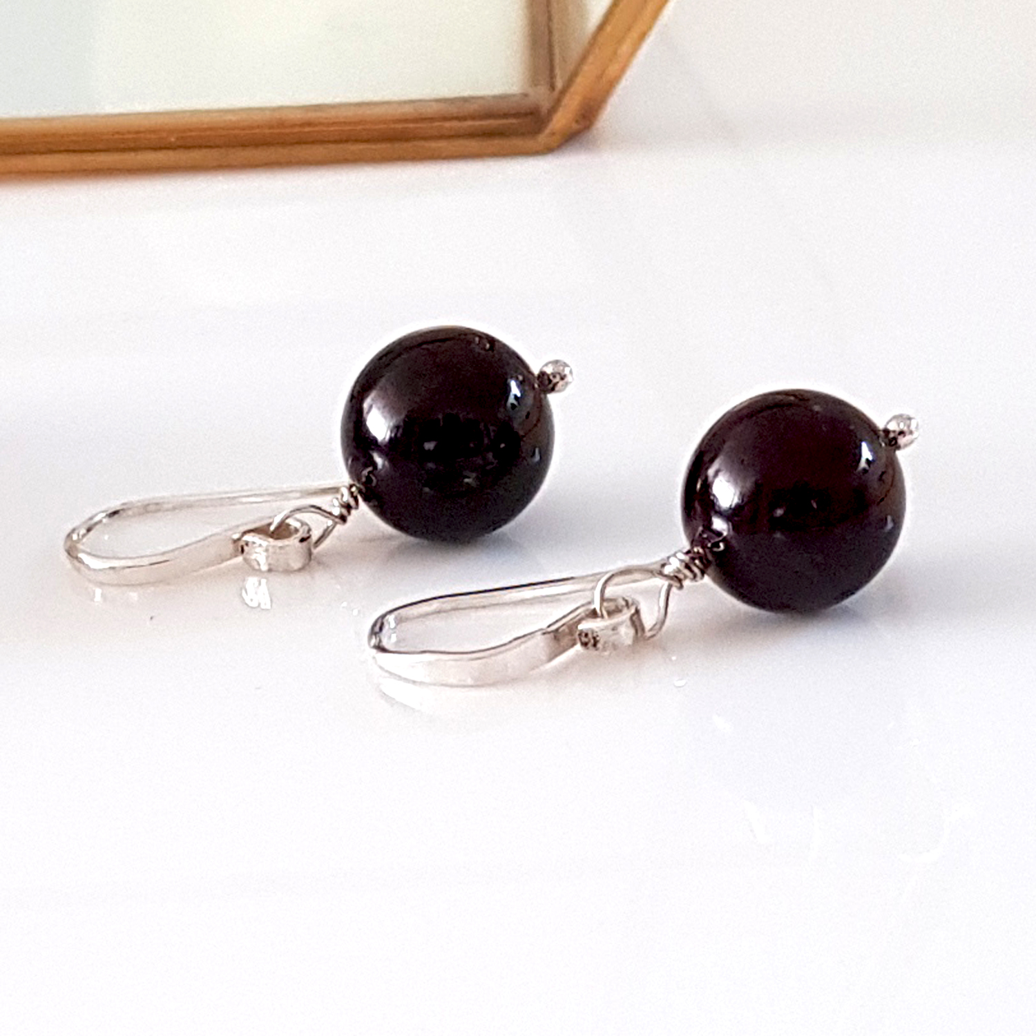 A pair of handmade Gem Ball Earrings featuring deep red garnet stones set in solid silver 925 French hooks, showcasing their elegant design.