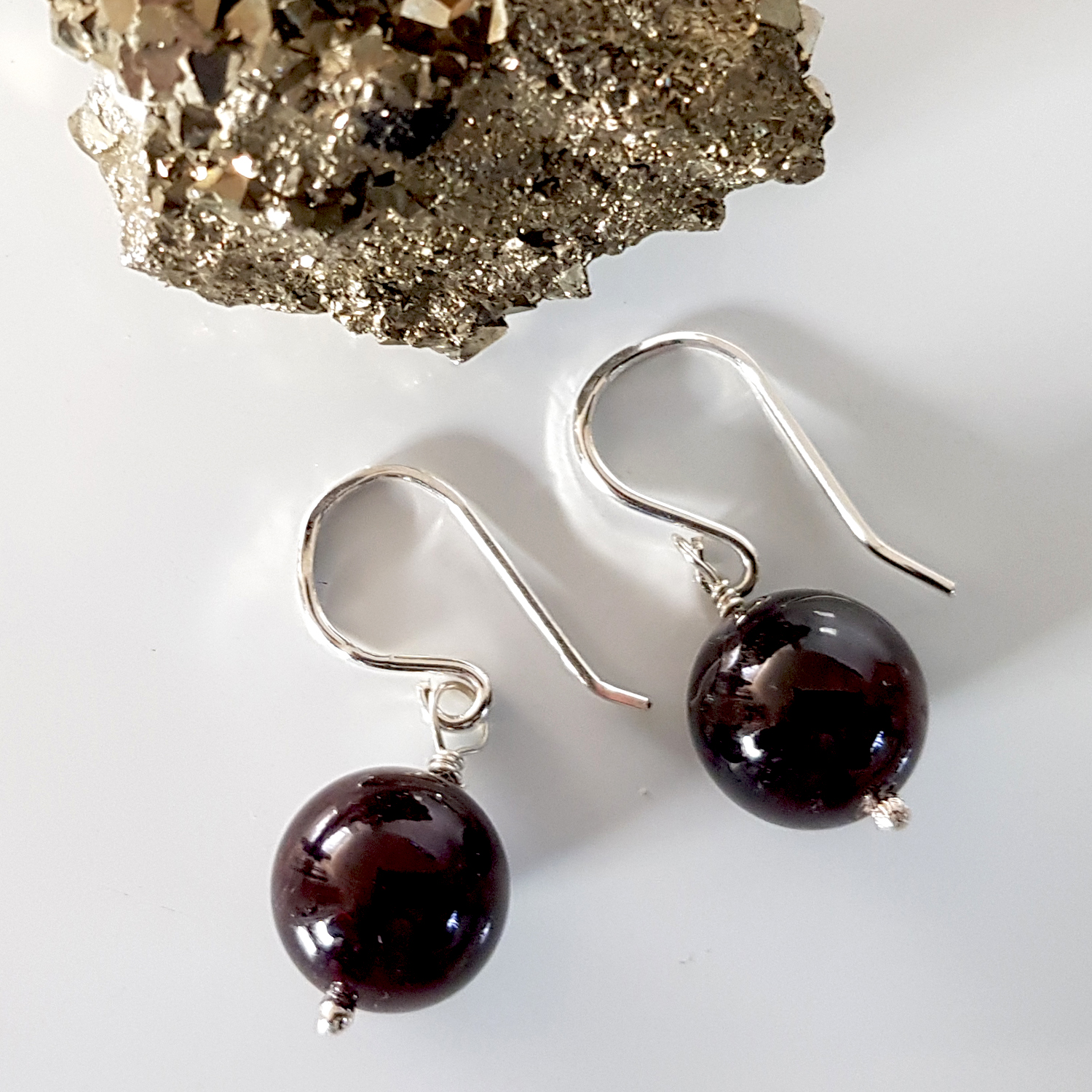 A pair of handmade Gem Ball Earrings featuring deep red garnet stones set in solid silver 925 French hooks, showcasing their elegant design.