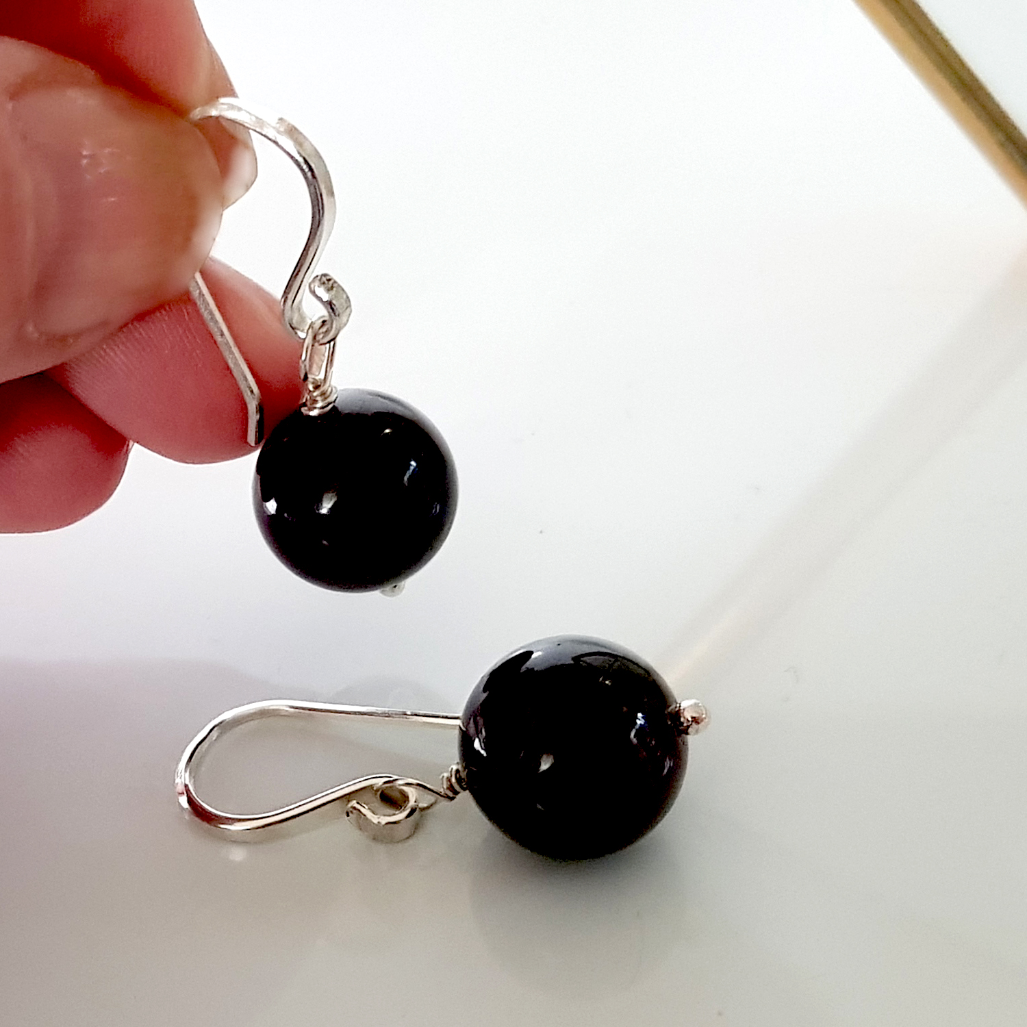 A pair of handmade Gem Ball Earrings featuring deep red garnet stones set in solid silver 925 French hooks, showcasing their elegant design.