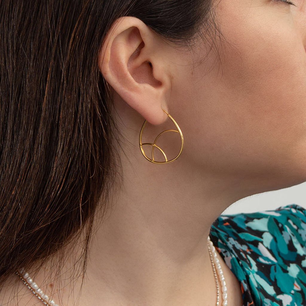 A pair of elegant geometric gold hoop earrings made from sterling silver and plated with 24K gold, showcasing a unique minimalist design.