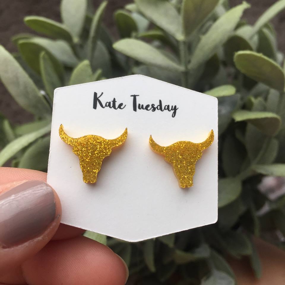 Golden steer head stud earrings made of sparkly acrylic, showcasing a unique and stylish design.