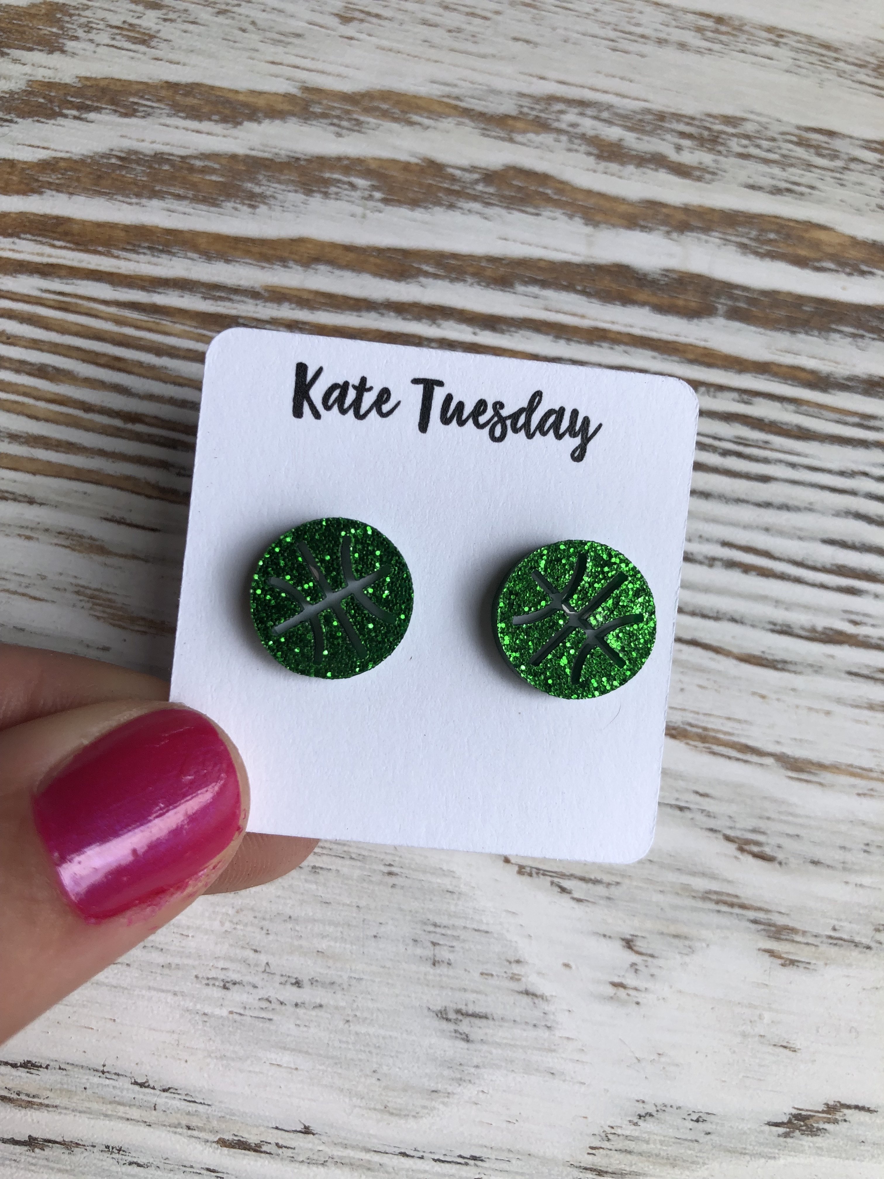 A pair of green basketball sparkly stud earrings made from acrylic, featuring a shiny finish and a playful design.