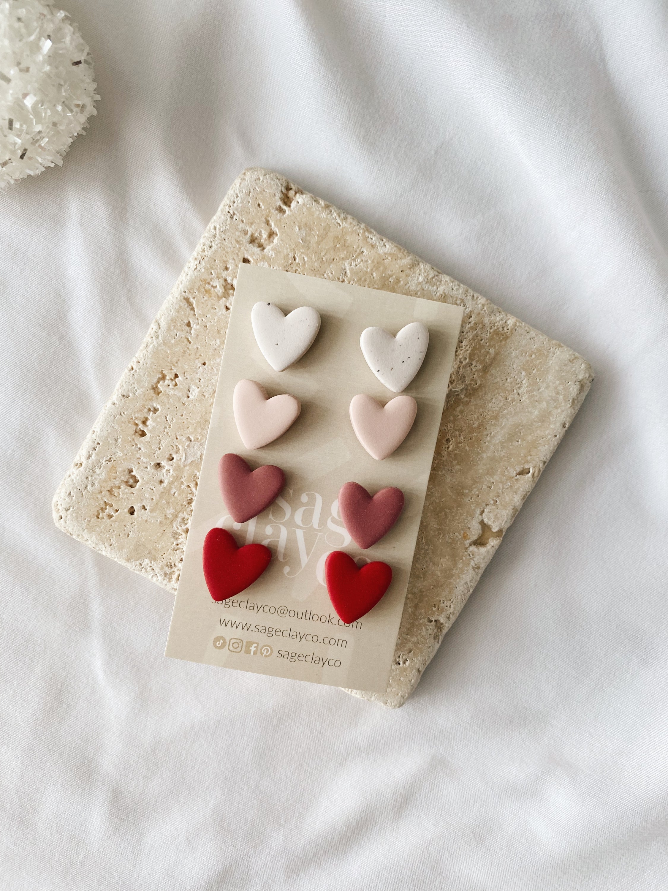 A pair of handmade polymer clay heart stud earrings in vibrant colors, showcasing their unique design and craftsmanship.