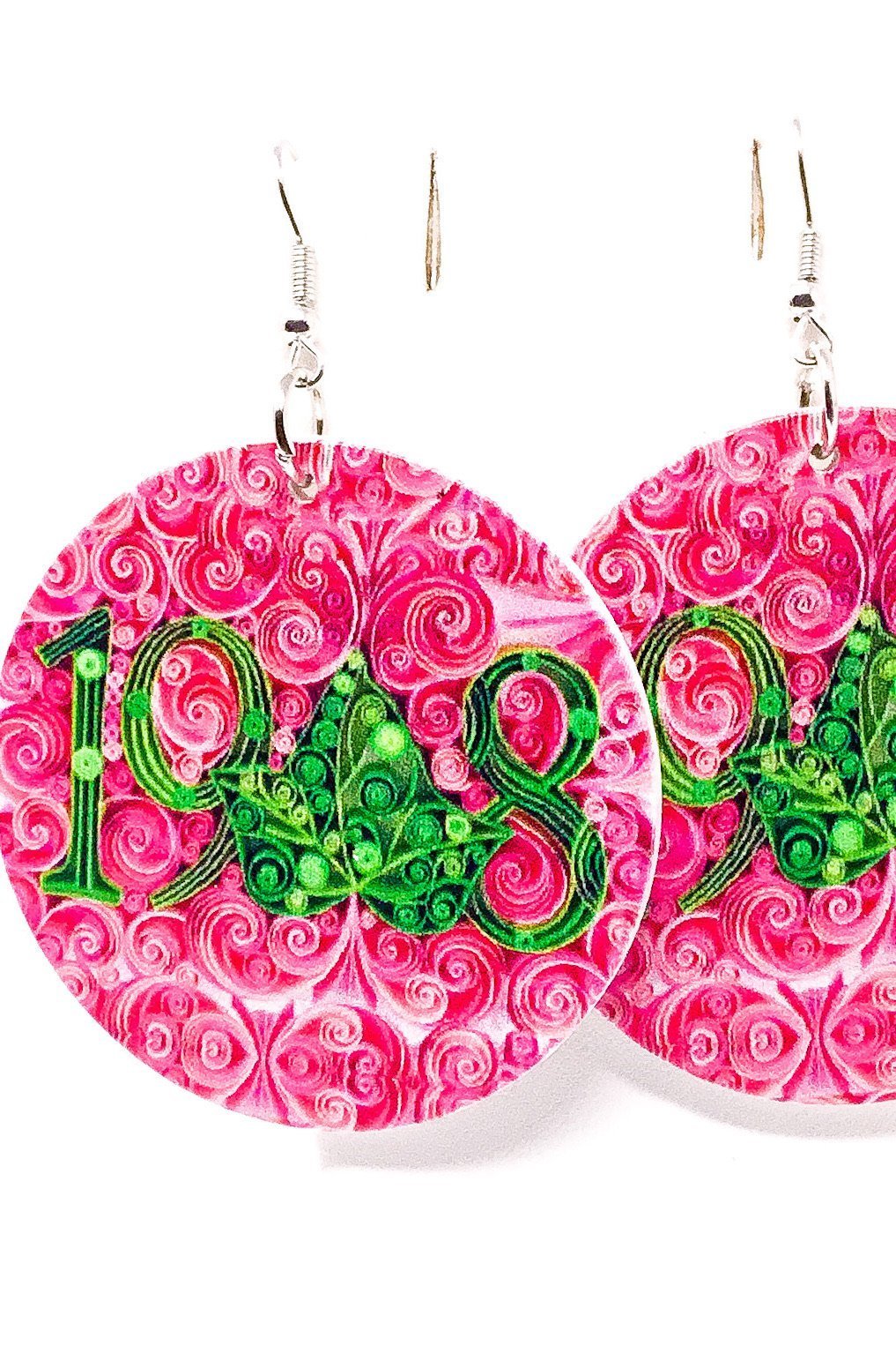 A pair of handmade wooden hoop drop earrings in pink and green, featuring a unique front and back print design with nickel-free brass ear hooks.