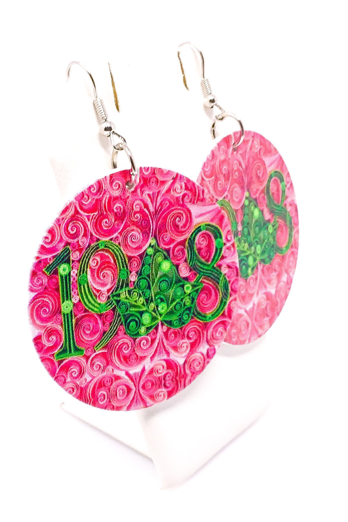 A pair of handmade wooden hoop drop earrings in pink and green, featuring a unique front and back print design with nickel-free brass ear hooks.