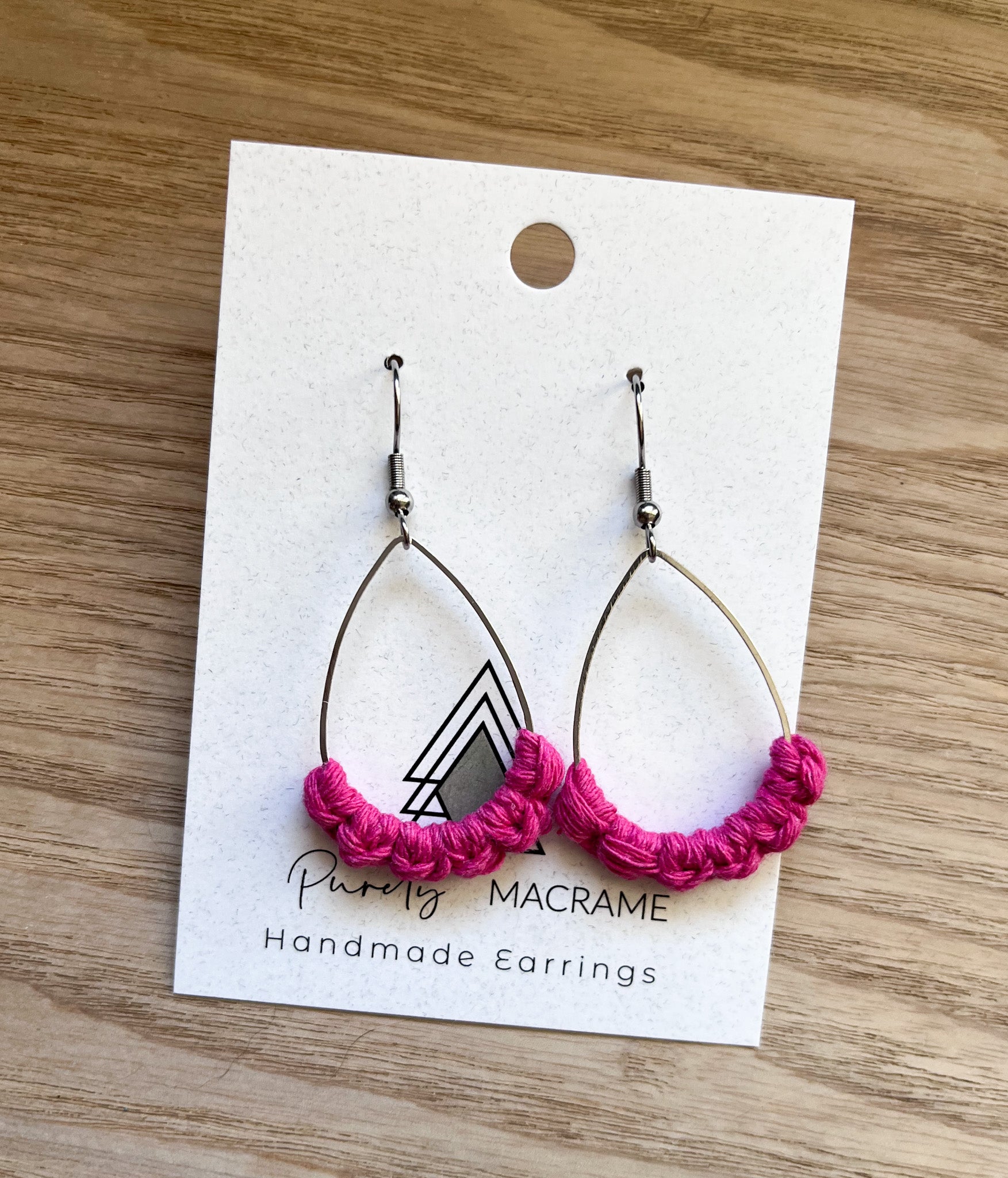 A pair of hot pink teardrop earrings with silver accents, made from 100% macrame cotton, showcasing a lightweight and stylish design.