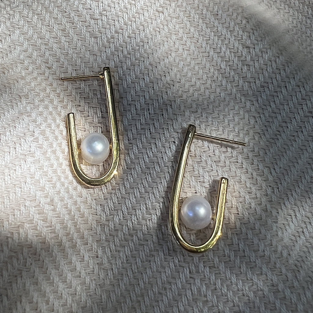 A pair of J Hoop Freshwater Pearl Earrings featuring recycled brass and elegant pearls, showcasing sustainable craftsmanship.