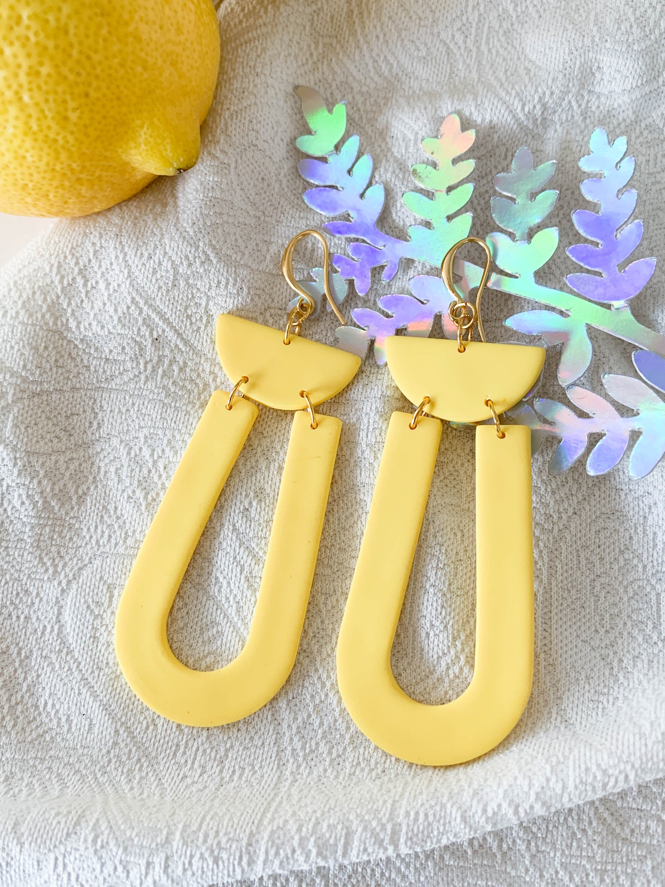 Josie Lemon geometric loop dangle earrings in bright yellow with gold plated hooks, showcasing a cheerful and modern design.