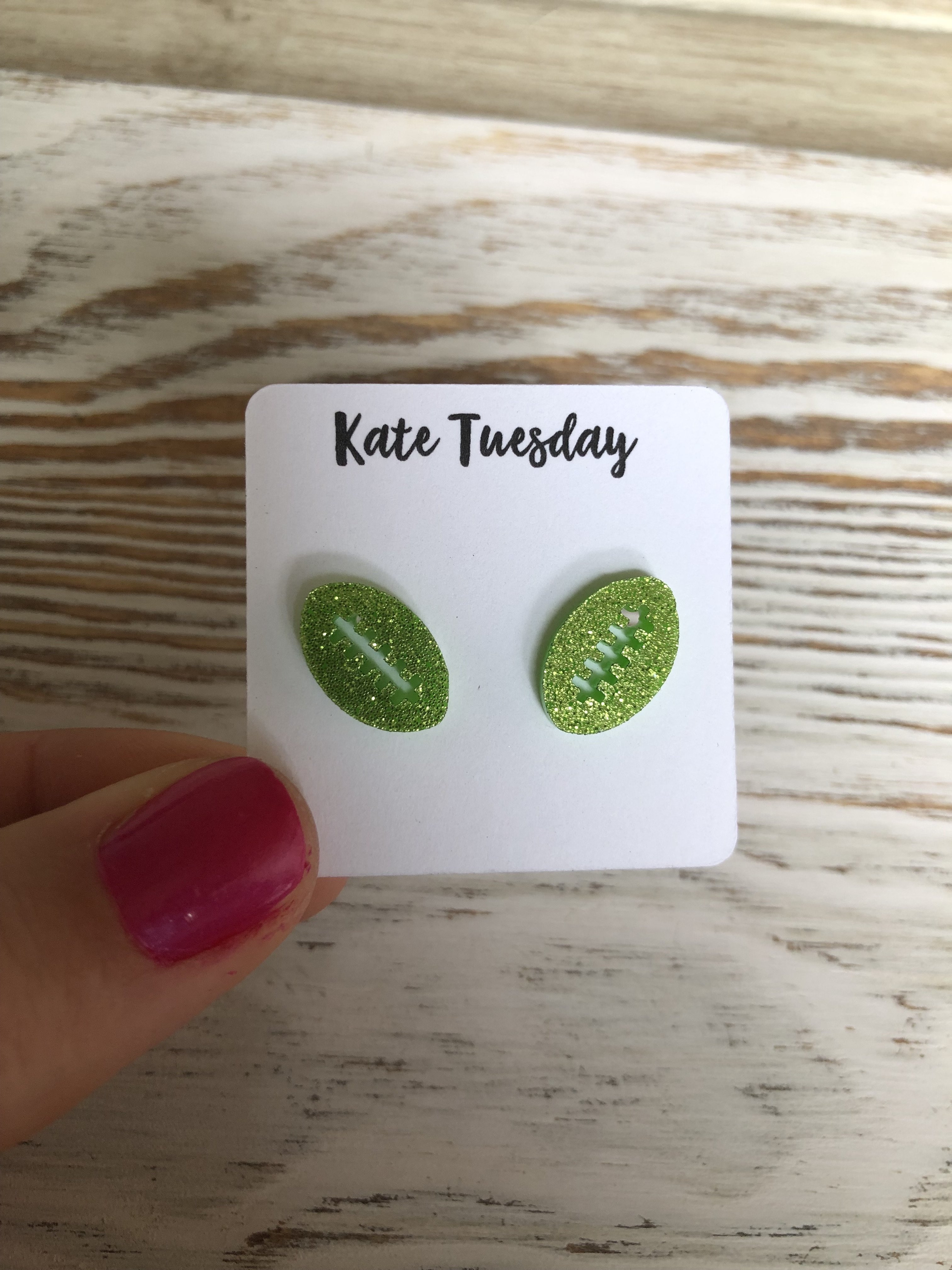 Lime green sparkly stud earrings shaped like footballs, made from acrylic material, showcasing a vibrant color and stylish design.