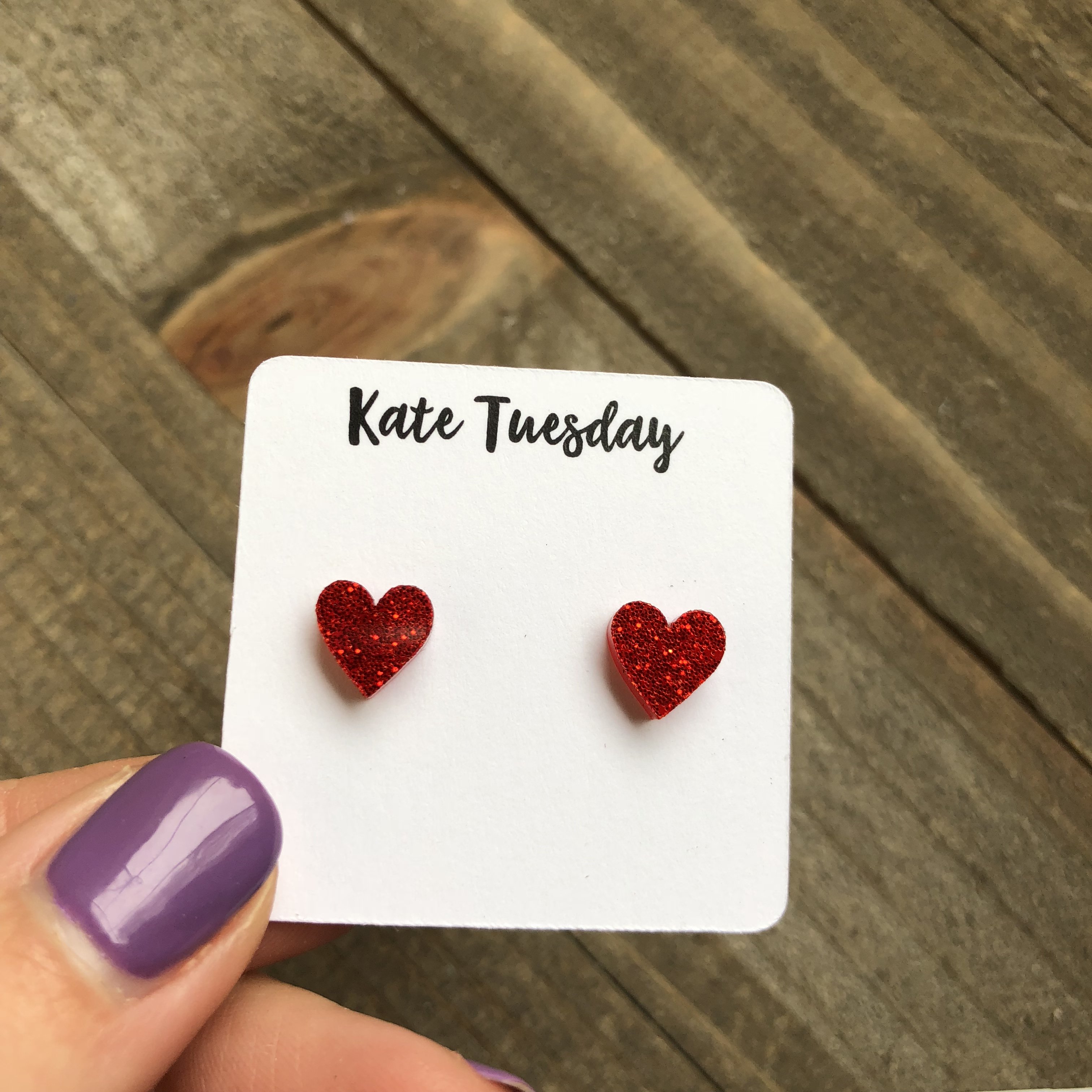 A pair of small 9mm red acrylic glitter heart earrings, perfect for kids, showcasing their sparkly design.