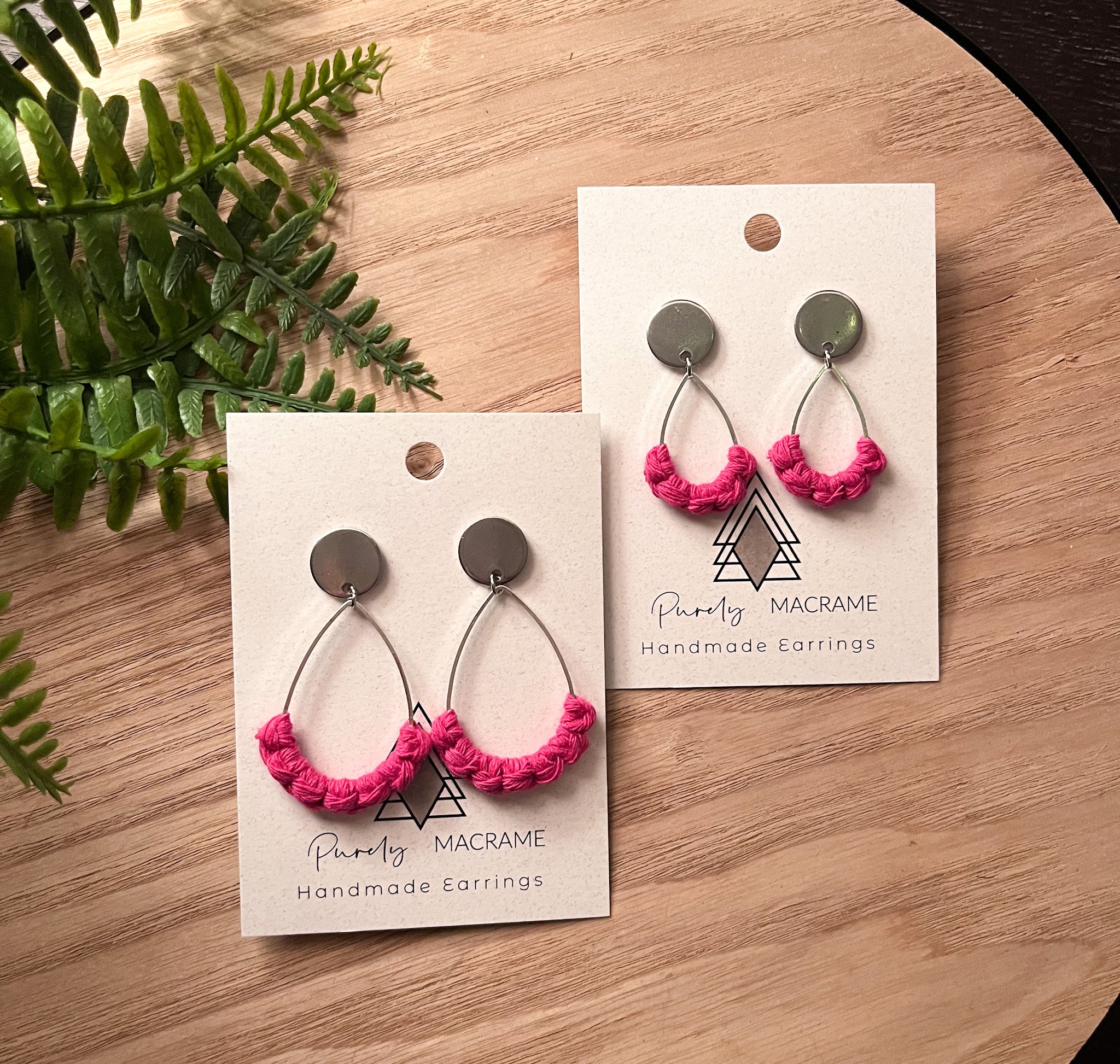 A pair of matching earrings for a mother and daughter, featuring vibrant hot pink colors, one small and one larger pair, designed for comfort and safety.