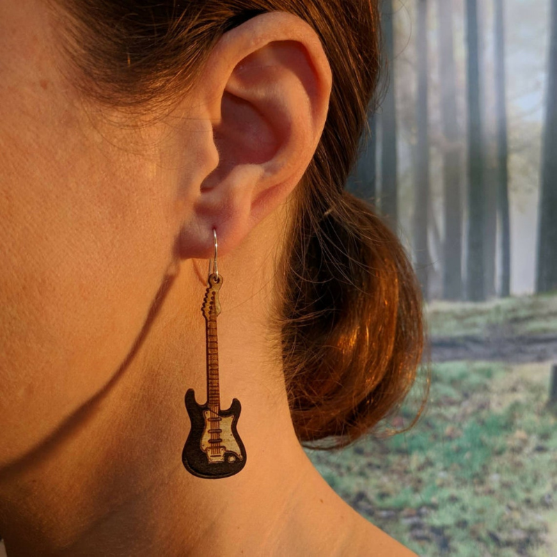 A pair of lightweight wooden earrings shaped like various musical instruments, including guitars and drums, with sterling silver ear wires.