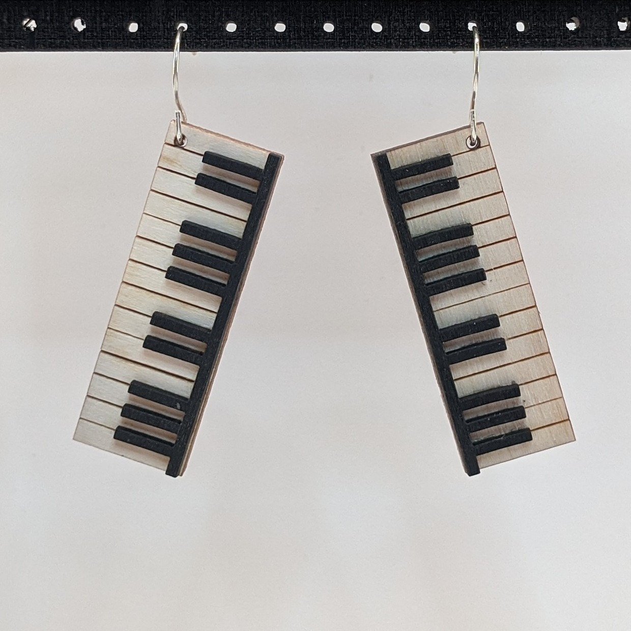 A pair of lightweight wooden earrings shaped like various musical instruments, including guitars and drums, with sterling silver ear wires.