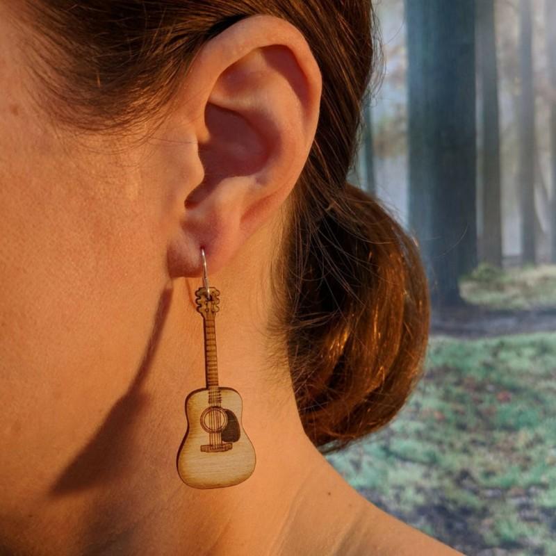 A pair of lightweight wooden earrings shaped like various musical instruments, including guitars and drums, with sterling silver ear wires.