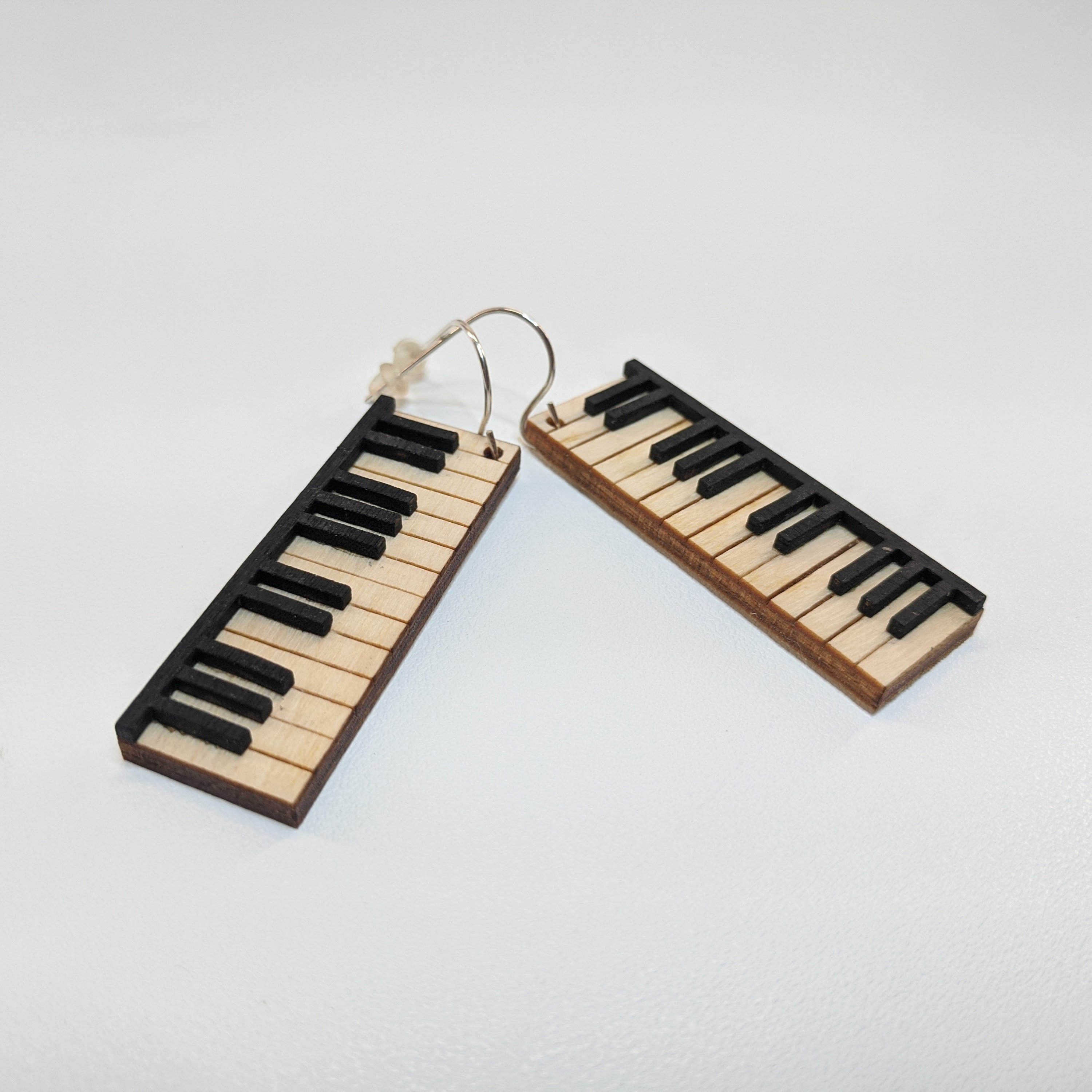 A pair of lightweight wooden earrings shaped like various musical instruments, including guitars and drums, with sterling silver ear wires.