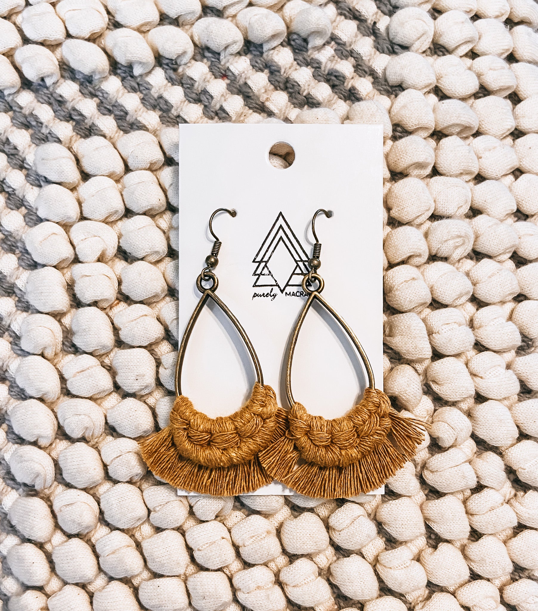 A pair of lightweight mustard teardrop earrings made from 100% macrame cotton, showcasing a stylish and eco-friendly design.