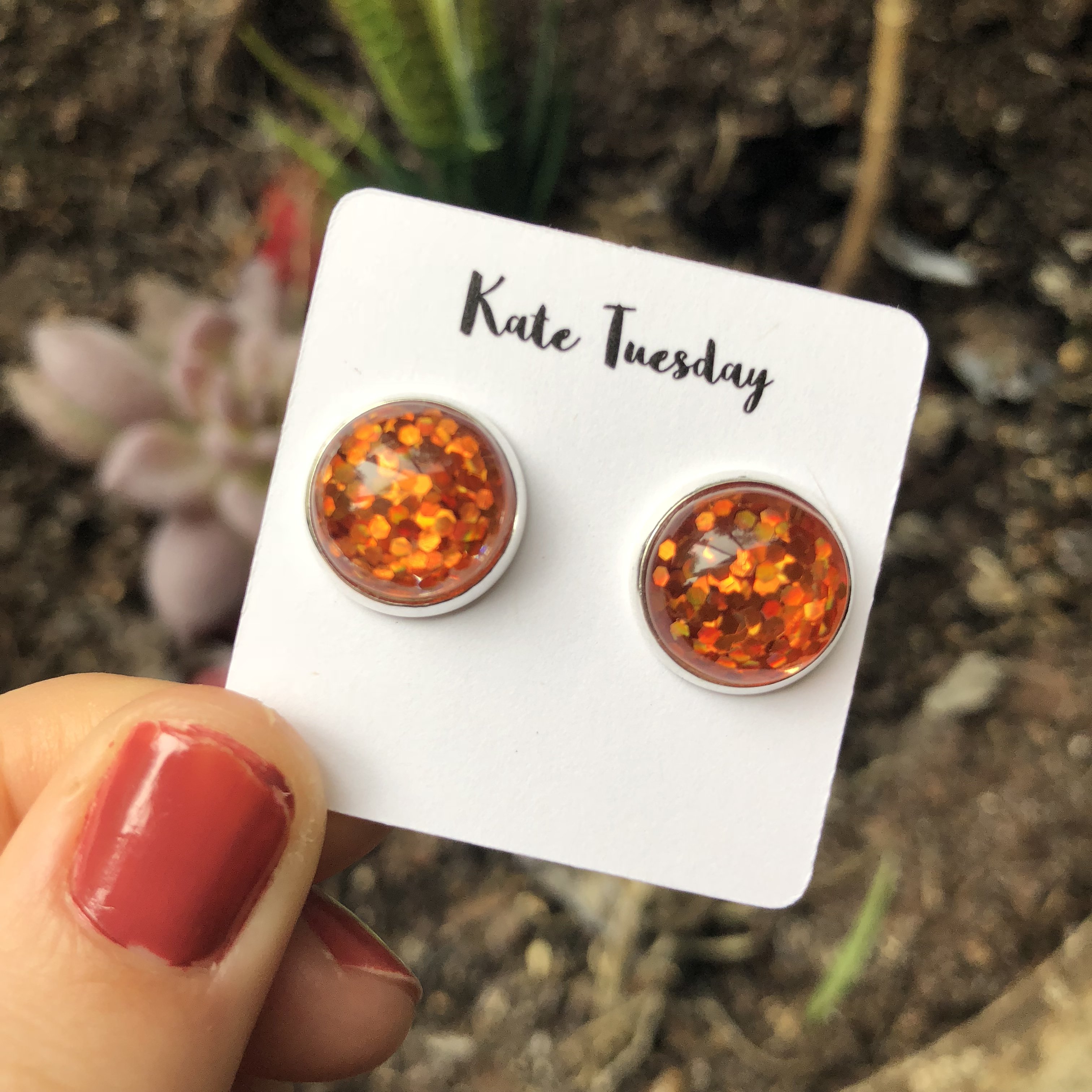 A pair of stunning orange glitter earrings with a sparkling finish, perfect for adding a vibrant touch to any outfit.