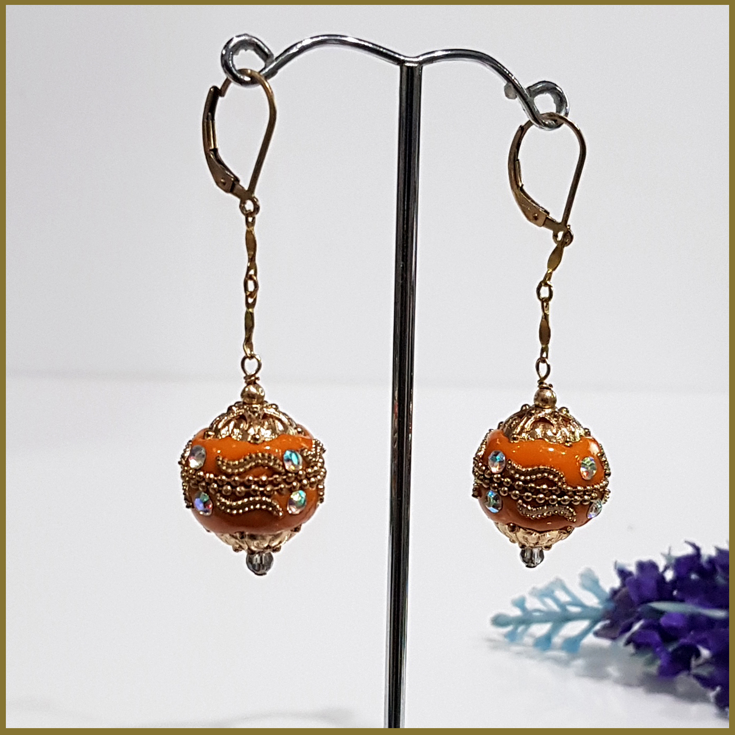 A pair of handmade orange long dangle earrings featuring Moroccan embellished beads on a gold filled chain, showcasing elegance and craftsmanship.