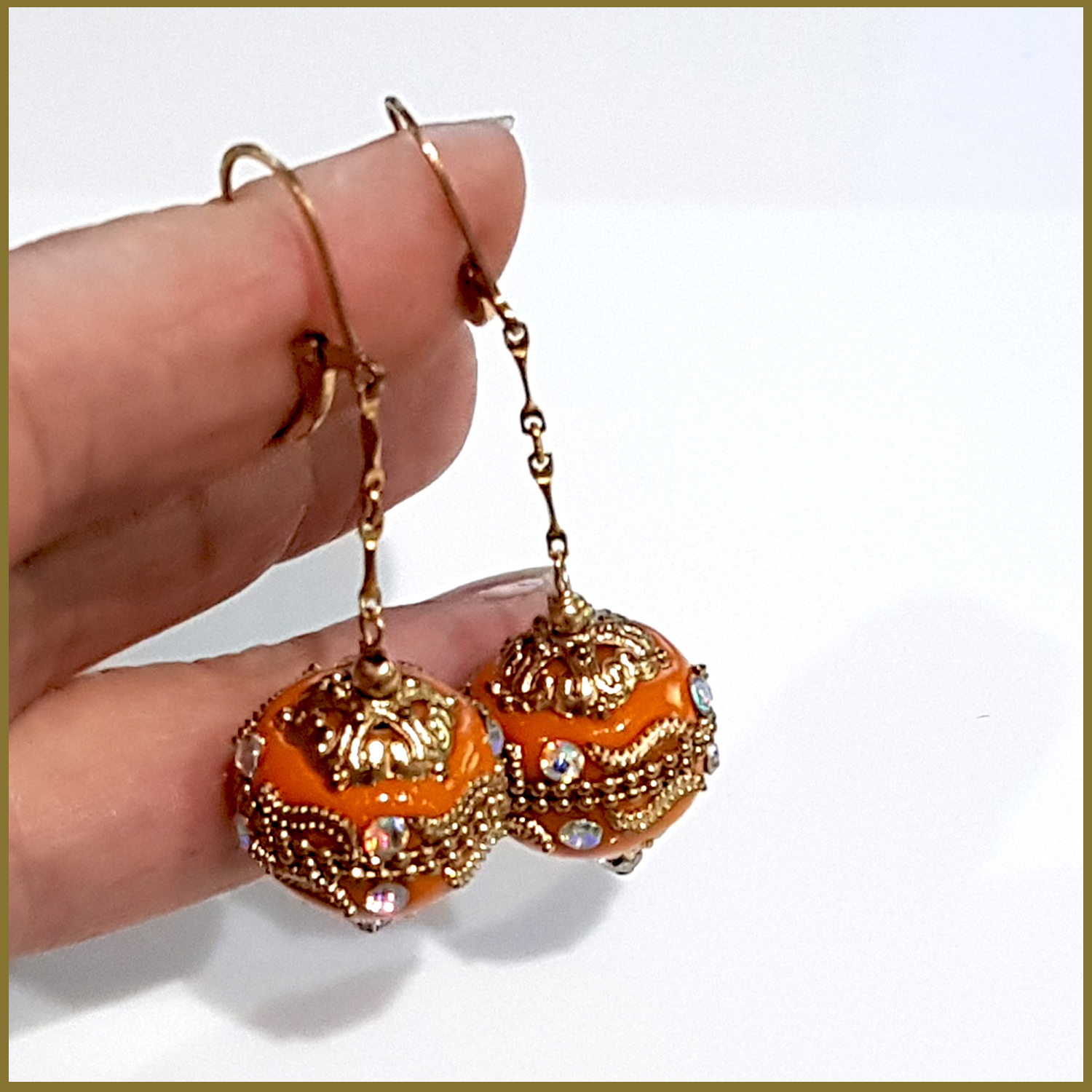 A pair of handmade orange long dangle earrings featuring Moroccan embellished beads on a gold filled chain, showcasing elegance and craftsmanship.