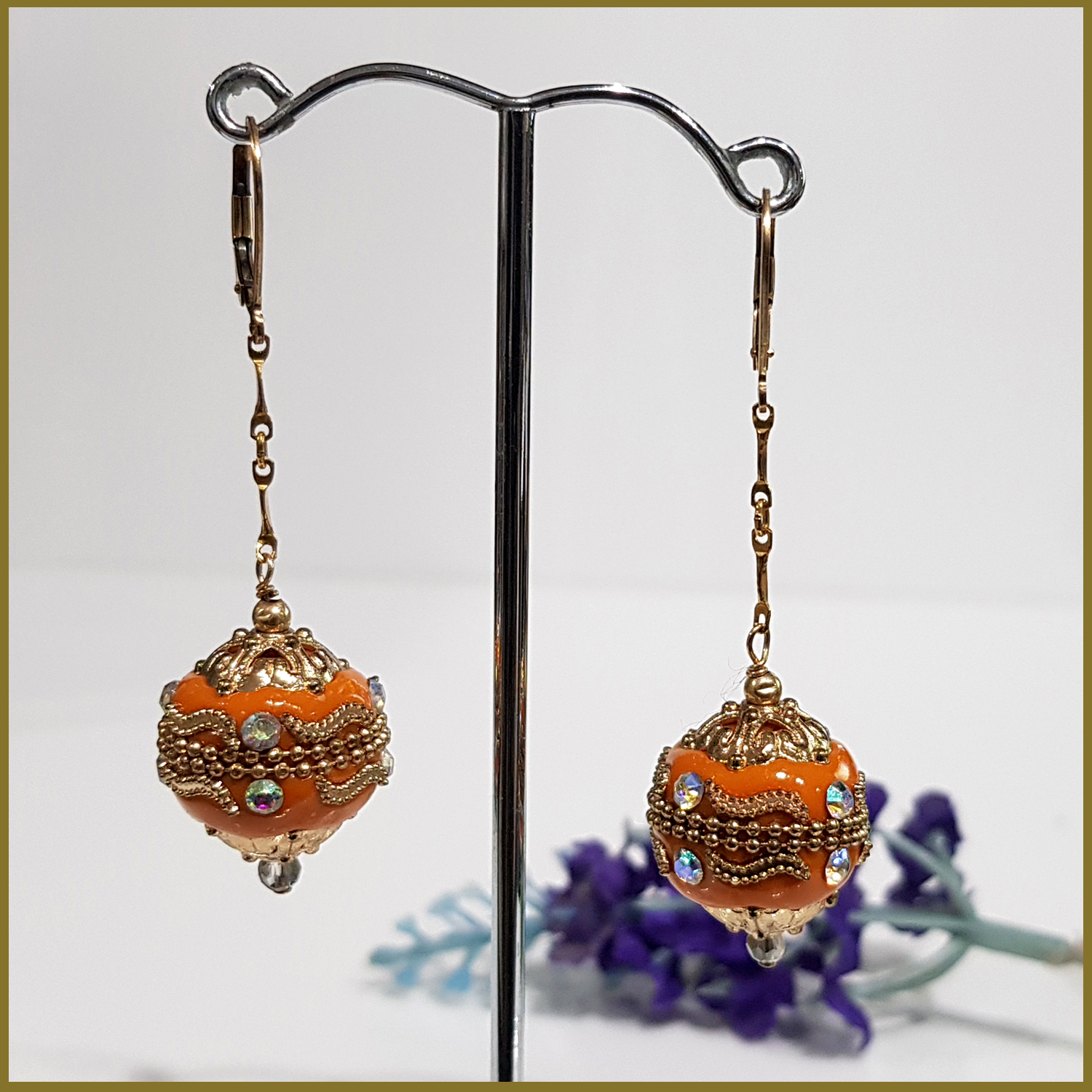 A pair of handmade orange long dangle earrings featuring Moroccan embellished beads on a gold filled chain, showcasing elegance and craftsmanship.